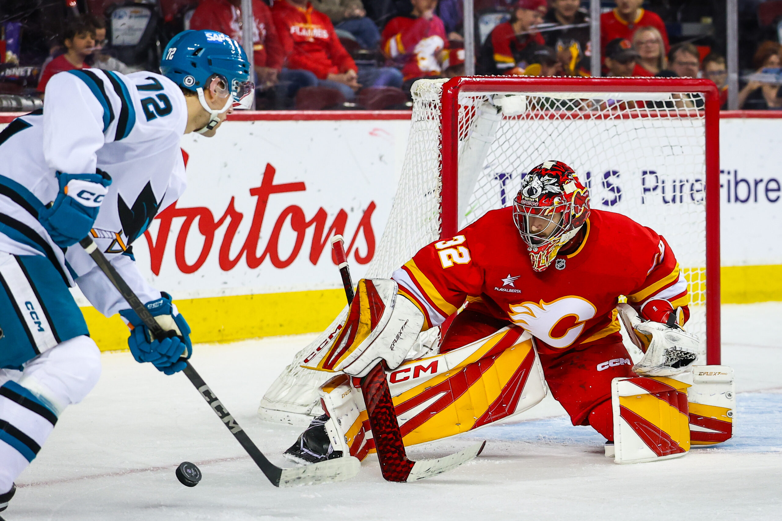 Apr 13, 2025; Calgary, Alberta, CAN; Calgary Flames goaltender Dustin Wolf (32) makes a save against San Jose Sharks left wing William Eklund (72) during the third period at Scotiabank Saddledome. Mandatory Credit: Sergei Belski-Imagn Images