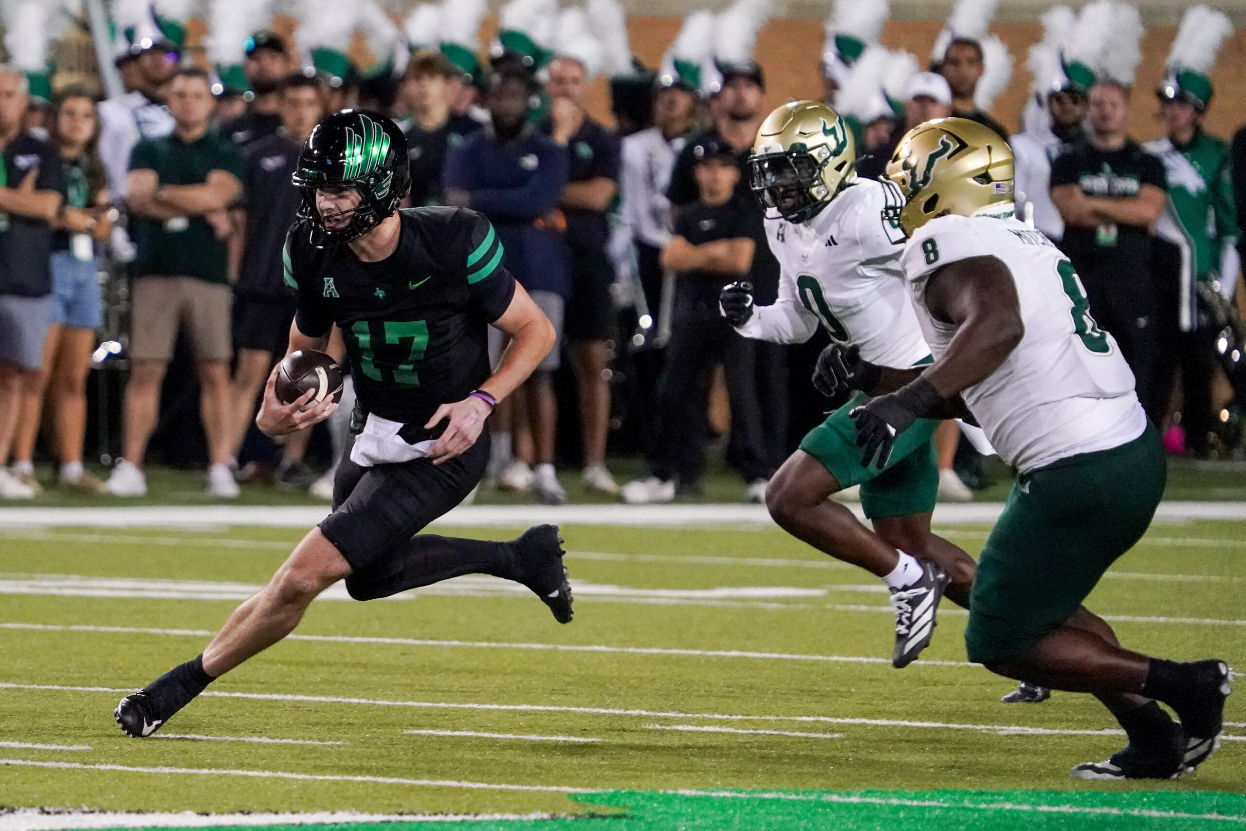 Oct 10, 2025; Denton, Texas, USA; North Texas Mean Green quarterback Drew Mestemaker (17) scrambles with the ball as South Florida Bulls cornerback Jarvis Lee (0) and defensive lineman Traevon Mitchell (8) defend during the first half of a game at DATCU Stadium. Mandatory Credit: Raymond Carlin III-Imagn Images