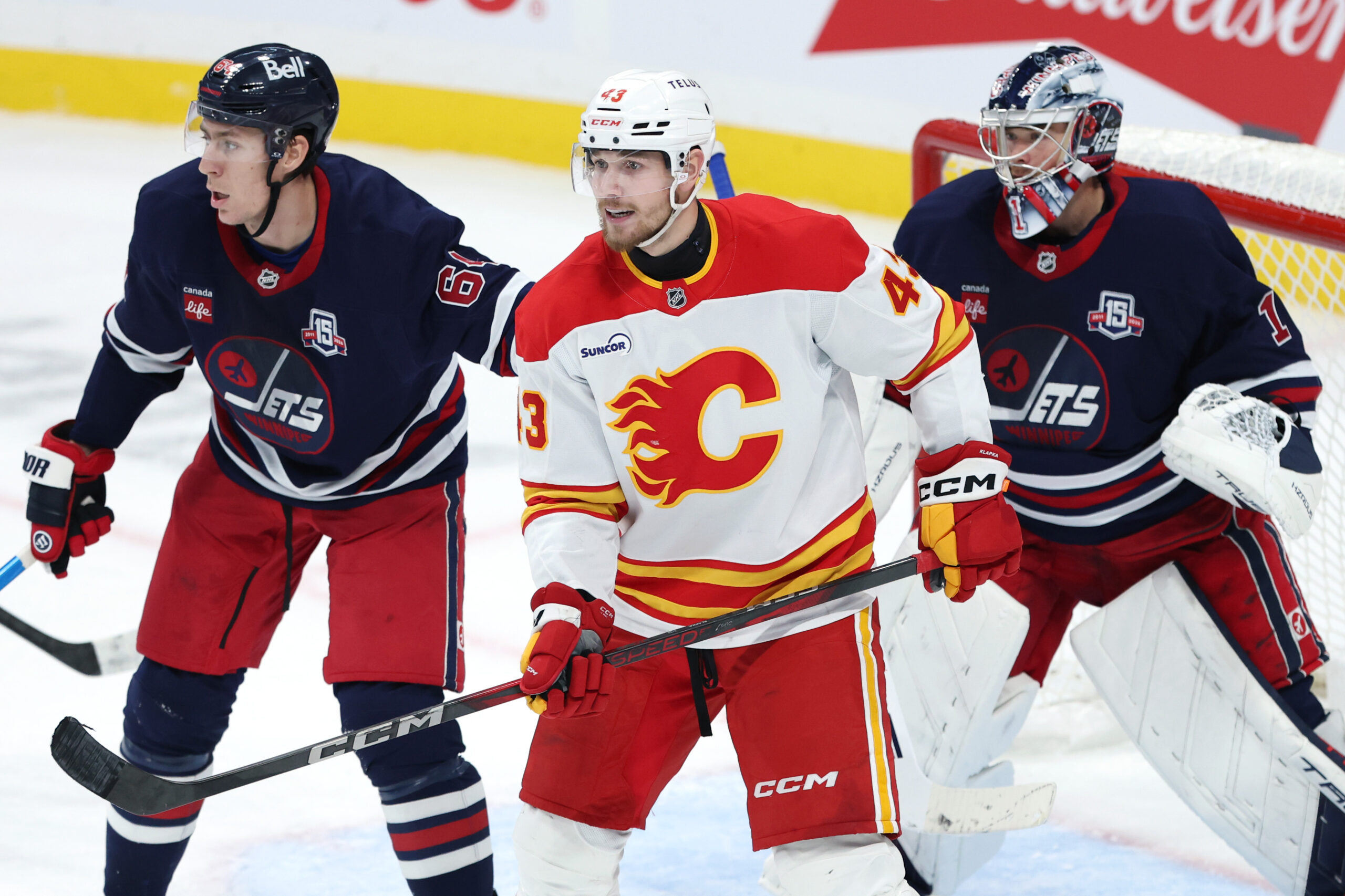 Oct 24, 2025; Winnipeg, Manitoba, CAN; Winnipeg Jets defenseman Logan Stanley (64), Calgary Flames right wing Adam Klapka (43) and Winnipeg Jets goaltender Eric Comrie (1) watch the play in the third period at Canada Life Centre. Mandatory Credit: James Carey Lauder-Imagn Images