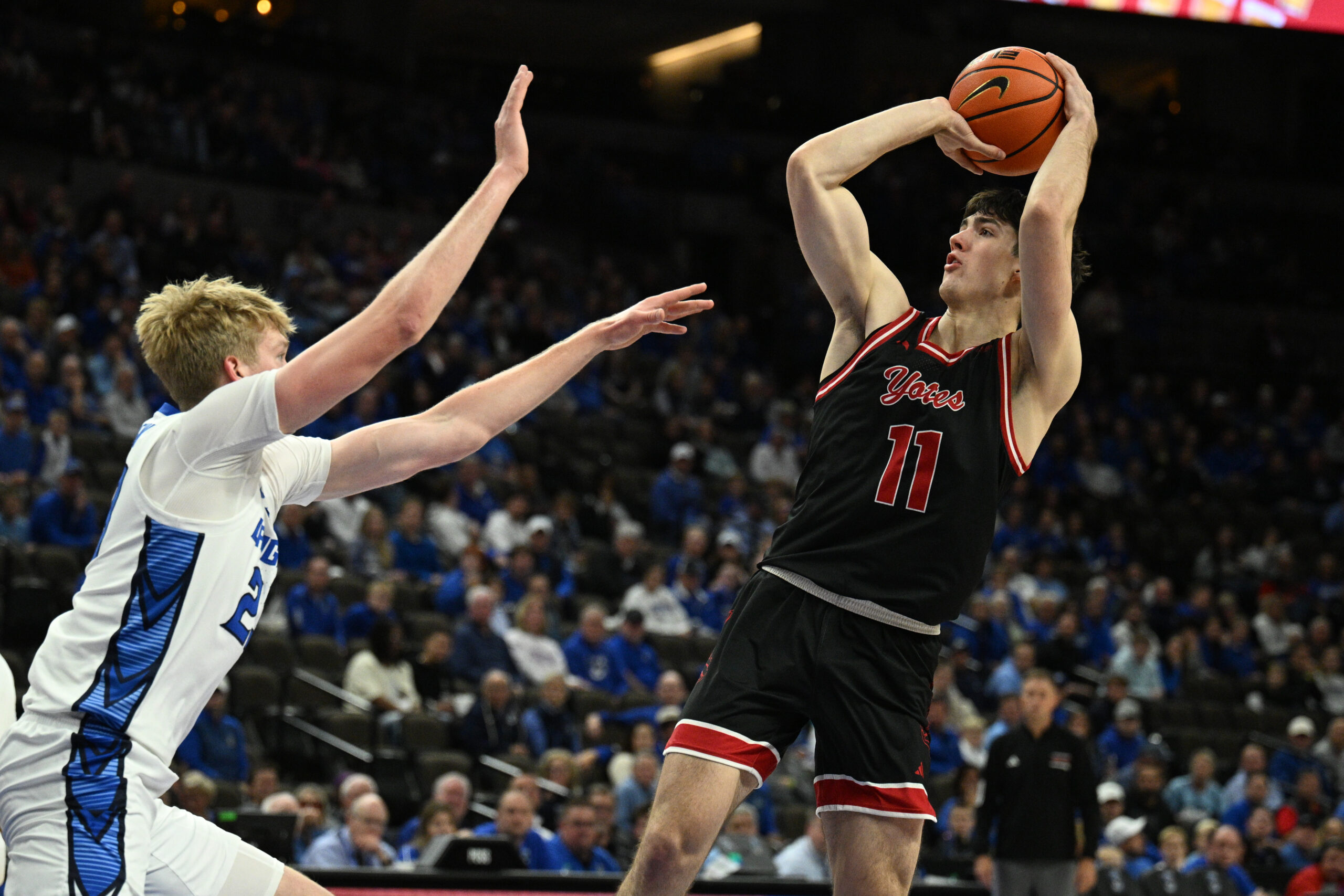 Nov 5, 2025; Omaha, Nebraska, USA;  South Dakota Coyotes guard Jesse McIntosh (11) attempts a shot over Creighton Bluejays forward Jackson McAndrew (23) during the first half at CHI Health Center Omaha. Mandatory Credit: Steven Branscombe-Imagn Images