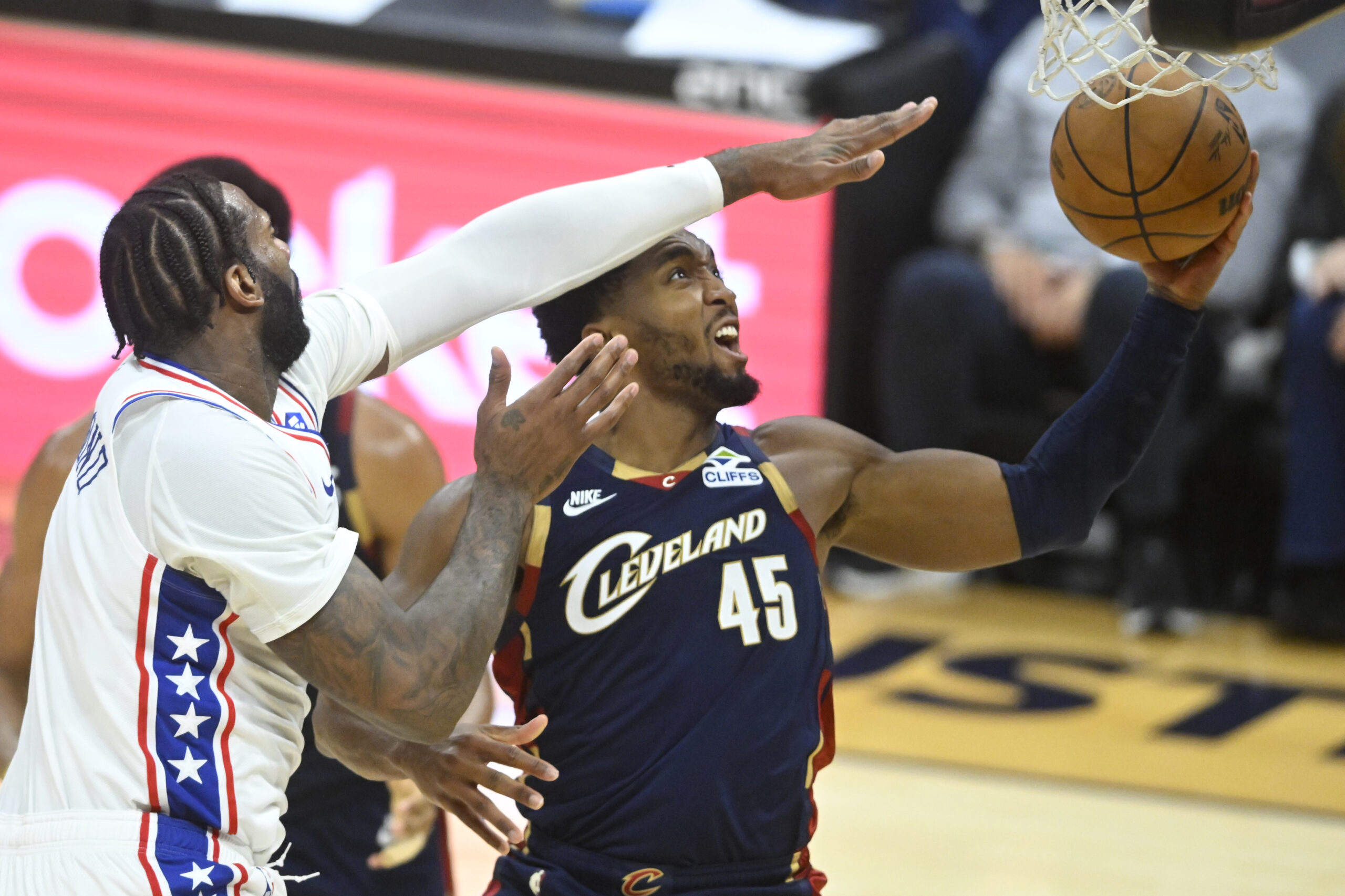 Nov 5, 2025; Cleveland, Ohio, USA; Cleveland Cavaliers guard Donovan Mitchell (45) drives to the basket beside Philadelphia 76ers center Andre Drummond (1) in the fourth quarter at Rocket Arena. Mandatory Credit: David Richard-Imagn Images