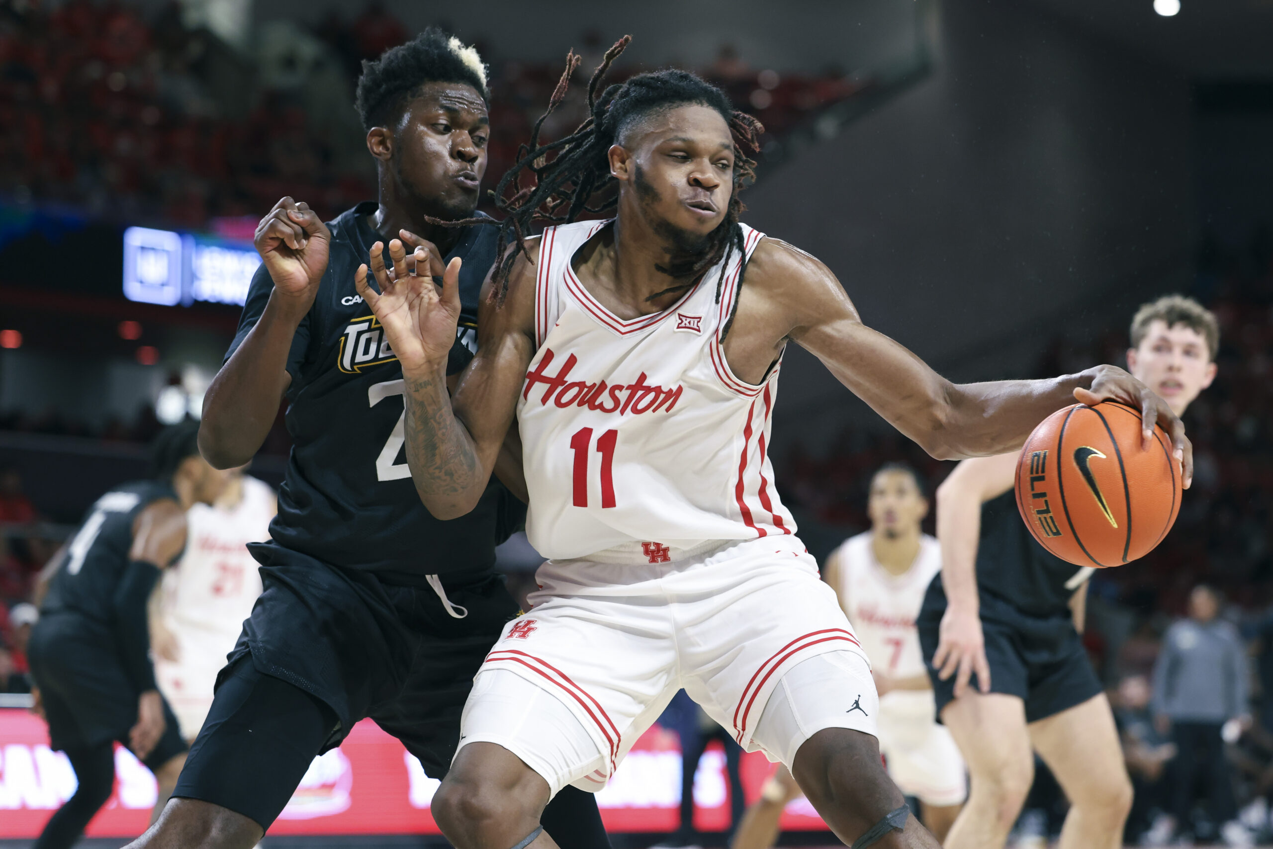 Nov 8, 2025; Houston, Texas, USA; Houston Cougars forward Joseph Tugler (11) attempts to control the ball as Towson Tigers forward Caleb Embeya (23) defends during the second half at Fertitta Center. Mandatory Credit: Troy Taormina-Imagn Images