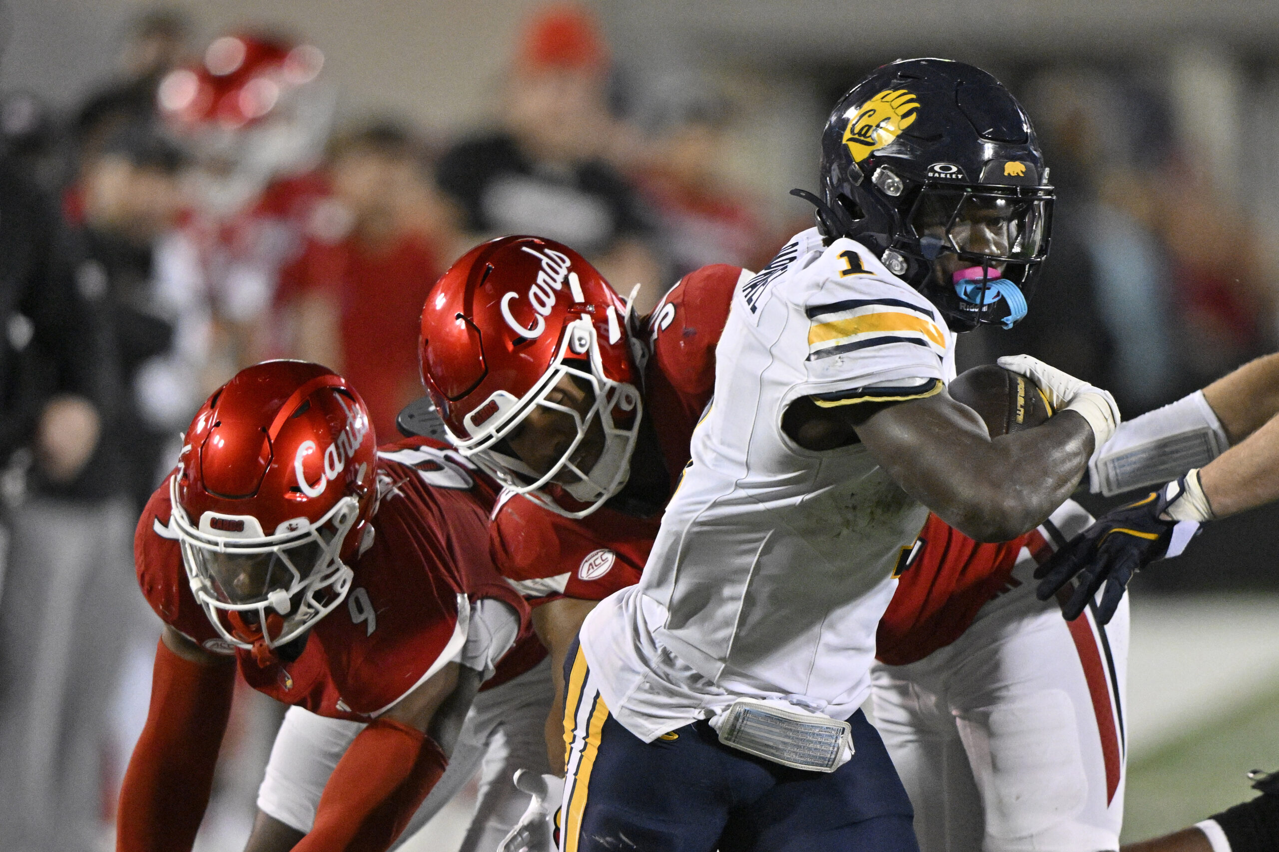 Nov 8, 2025; Louisville, Kentucky, USA;  California Golden Bears running back Kendrick Raphael (1) runs the ball against Louisville Cardinals defensive back Antonio Watts (9) and linebacker T.J. Quinn (34) in overtime at L&N Federal Credit Union Stadium. California defeated Louisville 29-26. Mandatory Credit: Jamie Rhodes-Imagn Images
