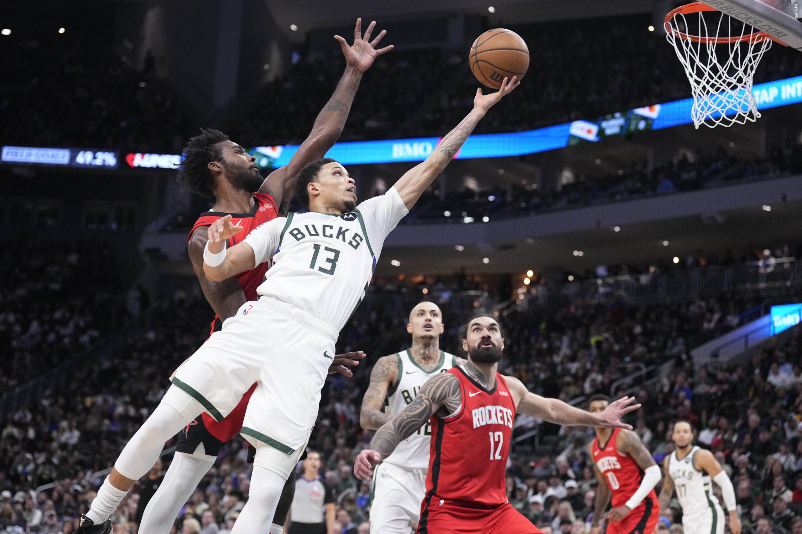 Nov 9, 2025; Milwaukee, Wisconsin, USA; Milwaukee Bucks guard Ryan Rollins (13) lays up a shot against Houston Rockets forward Tari Eason (17) in the second half at Fiserv Forum. Mandatory Credit: Michael McLoone-Imagn Images