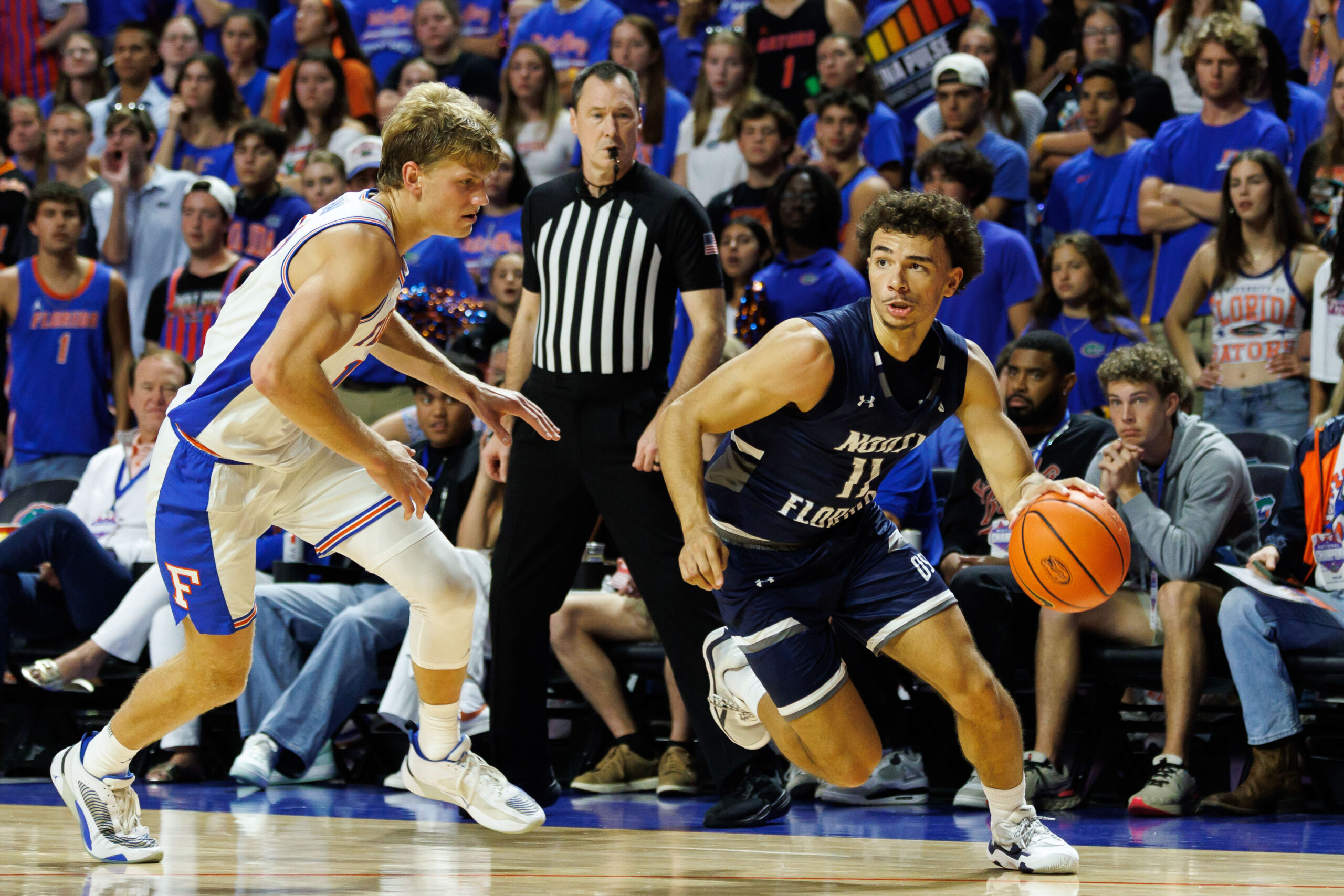 Nov 6, 2025; Gainesville, Florida, USA; North Florida Ospreys guard Kamrin Oriol (11) drives to the basket while Florida Gators forward Thomas Haugh (10) defends during the first half at Exactech Arena at the Stephen C. O'Connell Center. Mandatory Credit: Matt Pendleton-Imagn Images