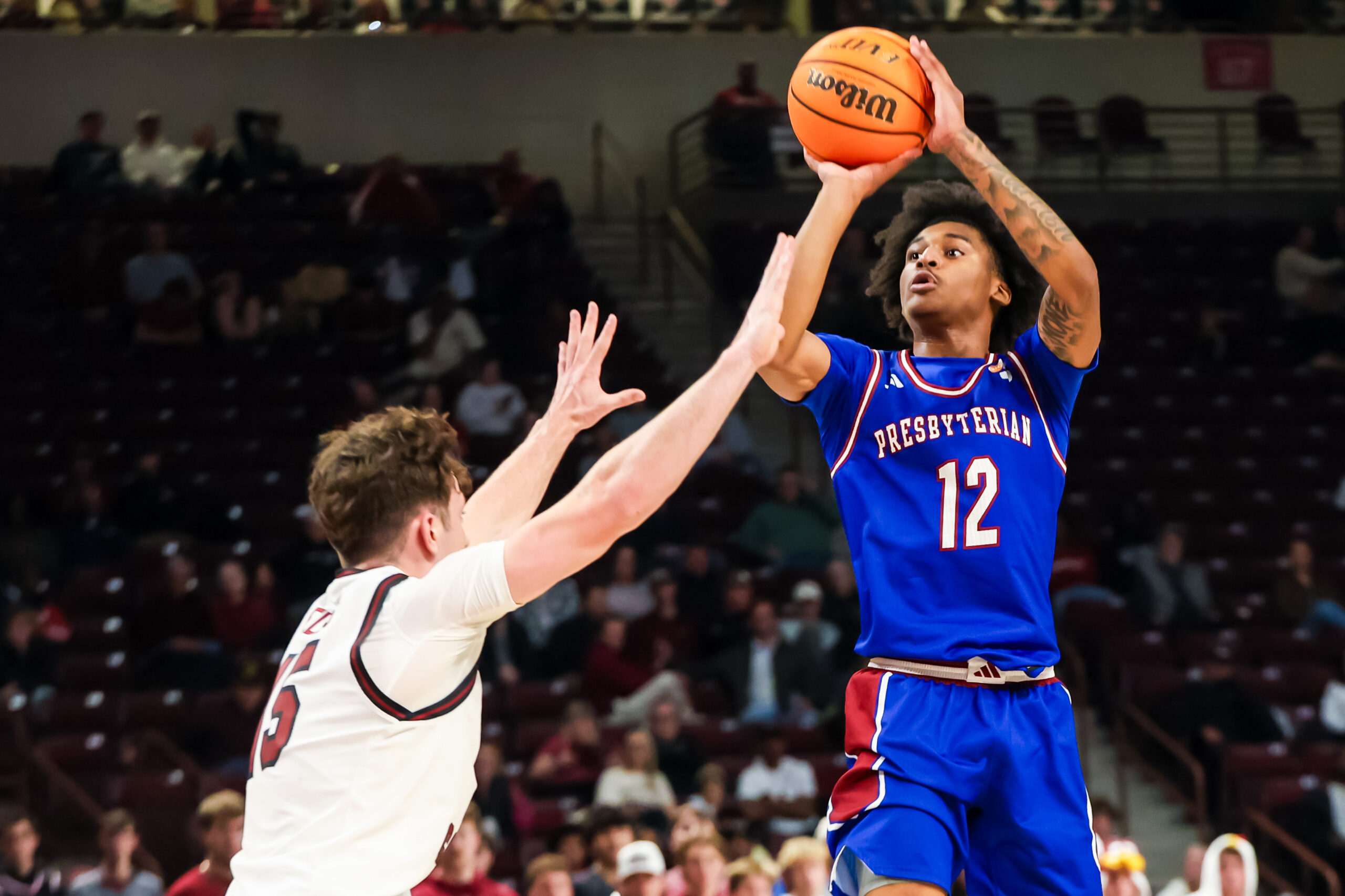 Nov 12, 2025; Columbia, South Carolina, USA; Presbyterian Blue Hose guard Carl Parrish (12) shoots over South Carolina Gamecocks guard Eli Ellis (15) in the second half at Colonial Life Arena. Mandatory Credit: Jeff Blake-Imagn Images