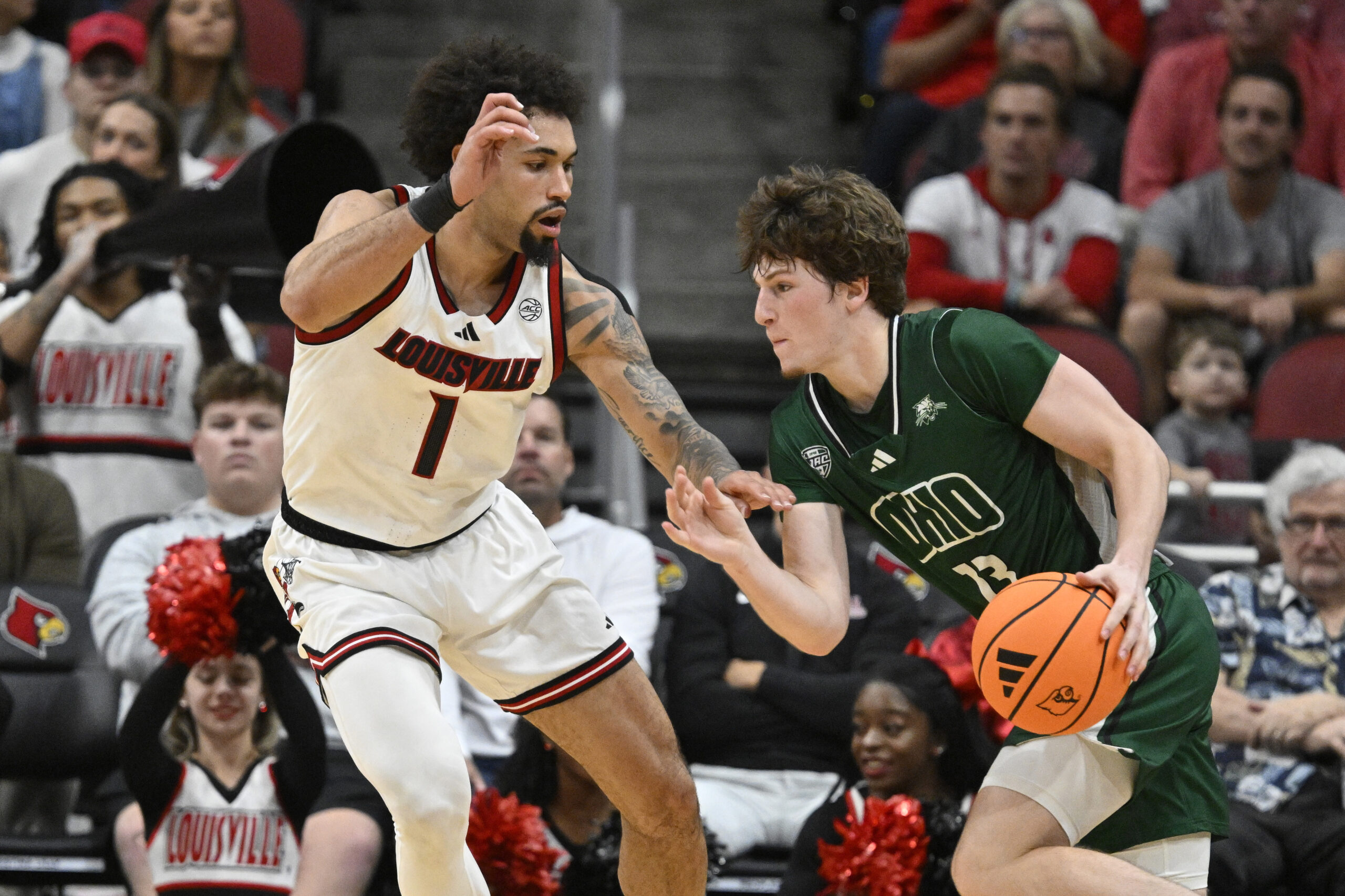 Nov 15, 2025; Louisville, Kentucky, USA;  Ohio Bobcats guard Jackson Paveletzke (13) dribbles against Louisville Cardinals guard J'Vonne Hadley (1) during the second half at KFC Yum! Center. Louisville defeated Ohio 106-81. Mandatory Credit: Jamie Rhodes-Imagn Images