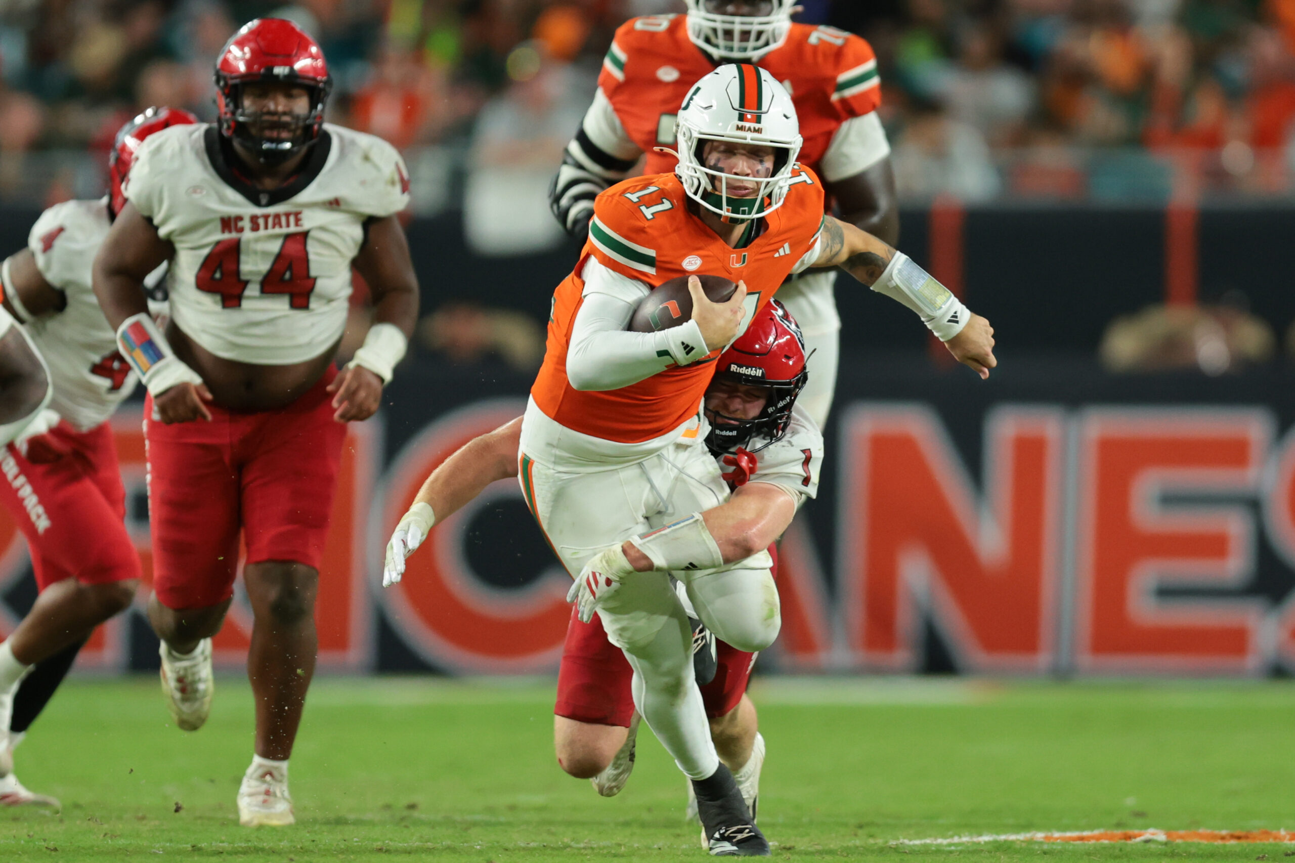 Nov 15, 2025; Miami Gardens, Florida, USA; Miami Hurricanes quarterback Carson Beck (11) carries the football against NC State Wolfpack linebacker Caden Fordham (1) during the third quarter at Hard Rock Stadium. Mandatory Credit: Sam Navarro-Imagn Images