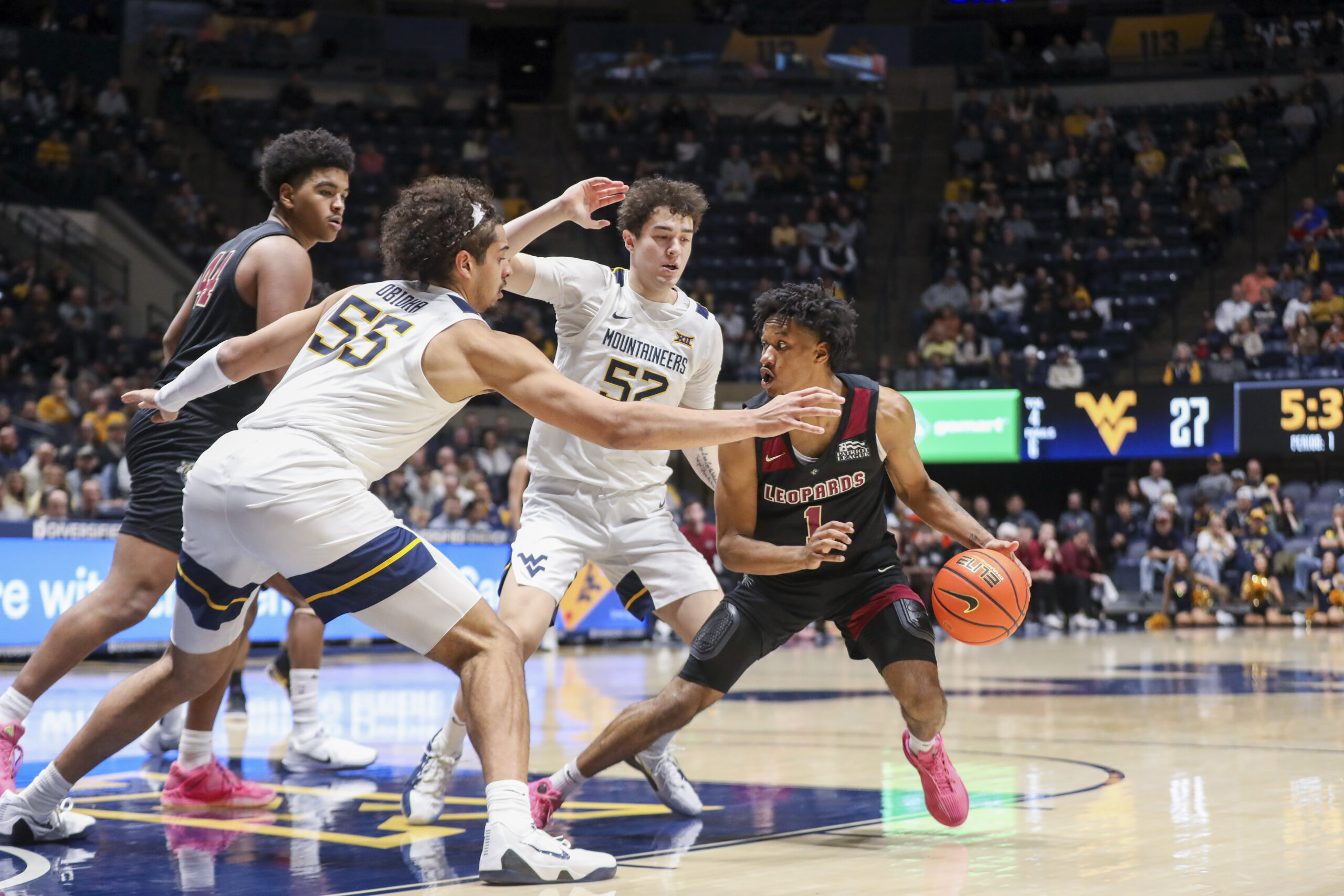 Nov 17, 2025; Morgantown, West Virginia, USA; Lafayette Leopards guard Caleb Williams (1) dribbles in the lane against West Virginia Mountaineers center Harlan Obioha (55) and West Virginia Mountaineers guard Treysen Eaglestaff (52) during the first half at WVU Coliseum. Mandatory Credit: Ben Queen-Imagn Images