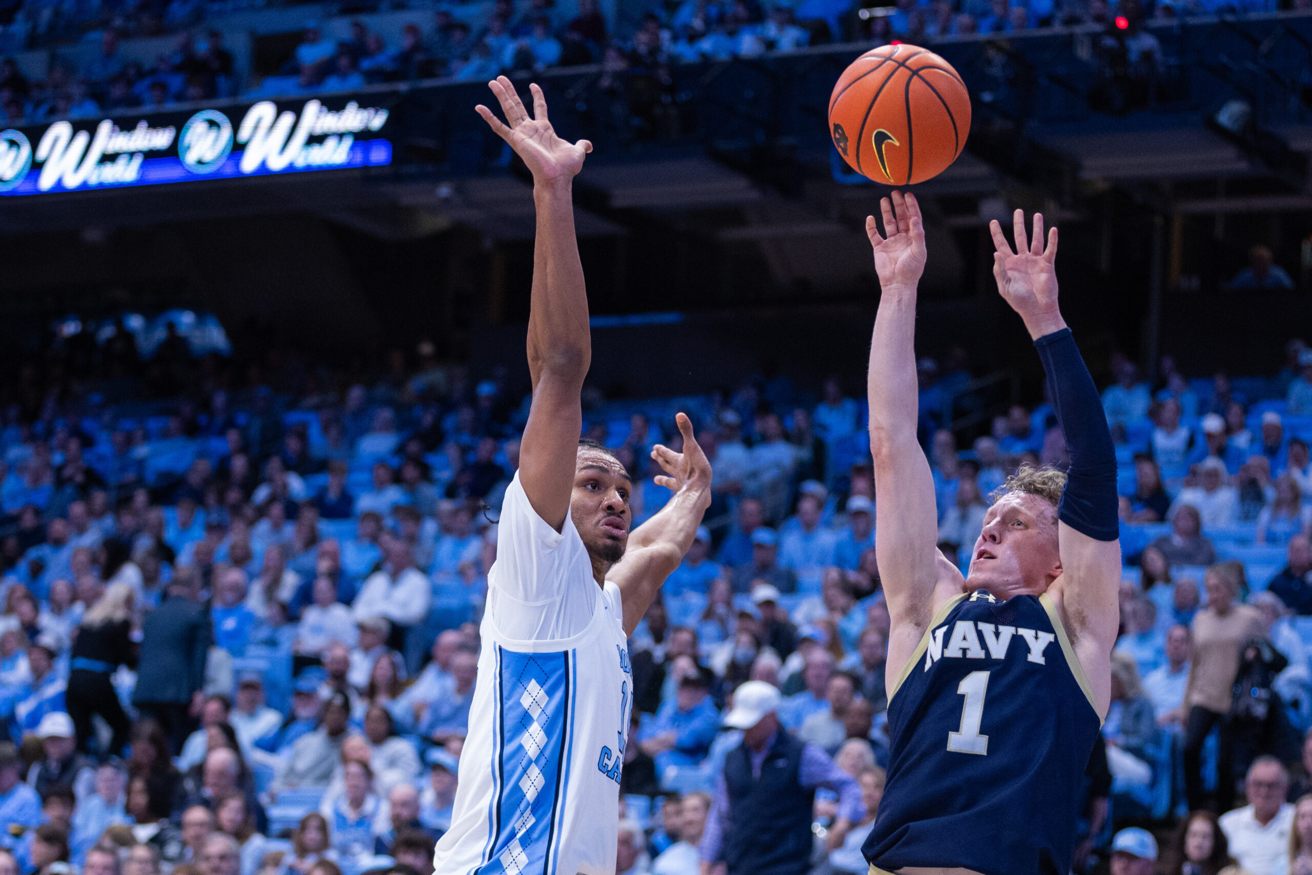 Nov 18, 2025; Chapel Hill, North Carolina, USA; Navy Midshipmen guard Austin Benigni (1) shoots against North Carolina Tar Heels forward Jarin Stevenson (15) during the first half at Dean E. Smith Center. Mandatory Credit: Scott Kinser-Imagn Images