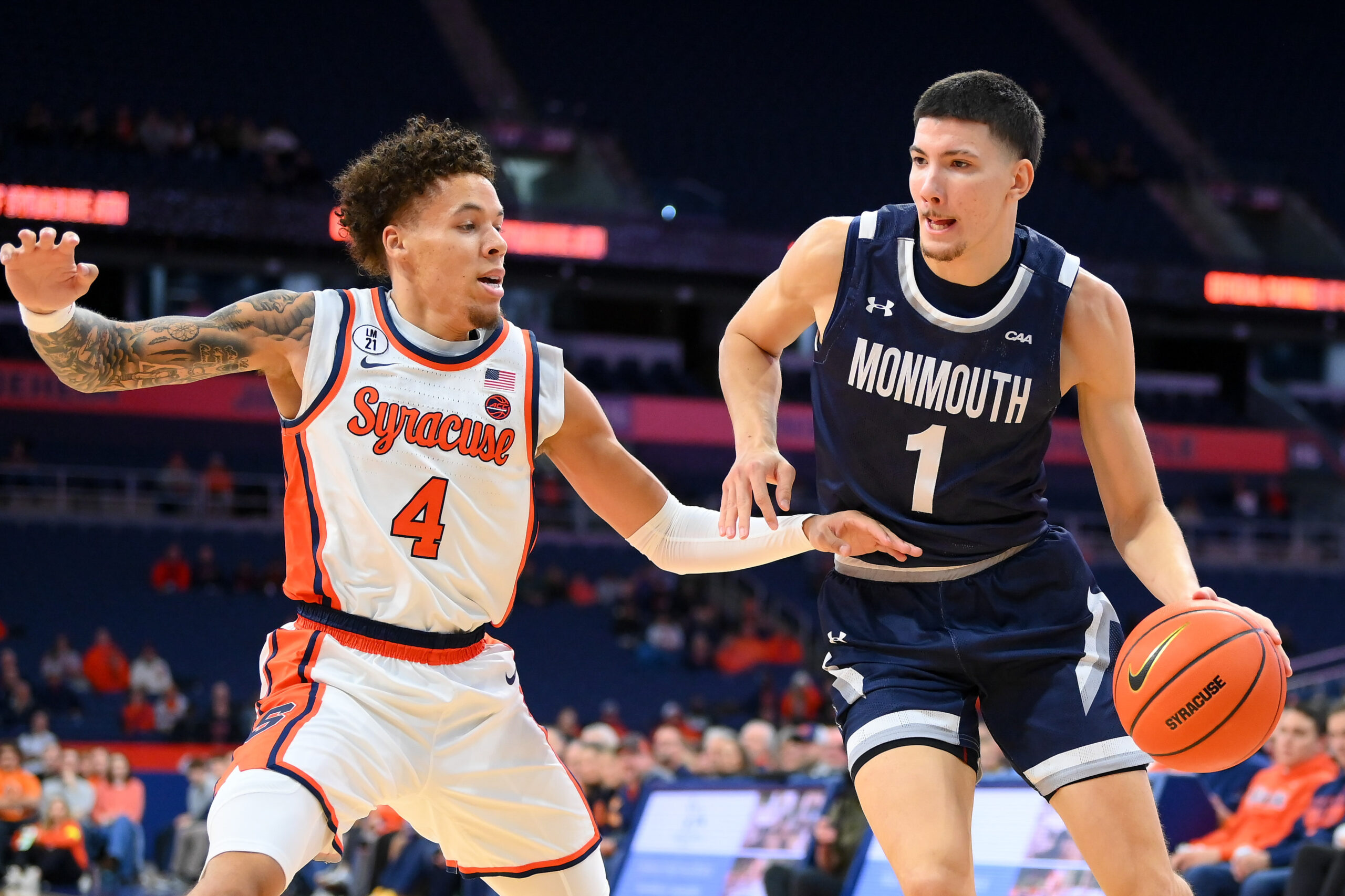 Nov 18, 2025; Syracuse, New York, USA; Monmouth Hawks forward Jason Rivera-Torres (1) drives against Syracuse Orange guard Nate Kingz (4) during the first half at the JMA Wireless Dome. Mandatory Credit: Rich Barnes-Imagn Images