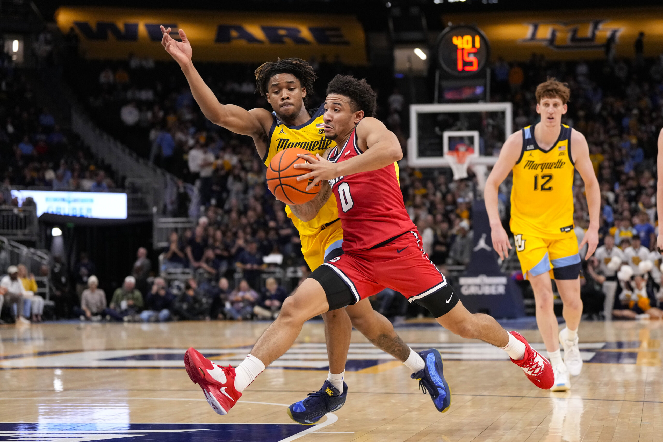 Nov 19, 2025; Milwaukee, Wisconsin, USA;  Dayton Flyers guard Javon Bennett (0) drives for the basket against Marquette Golden Eagles guard Nigel James Jr. (0) during the first half at Fiserv Forum. Mandatory Credit: Jeff Hanisch-Imagn Images