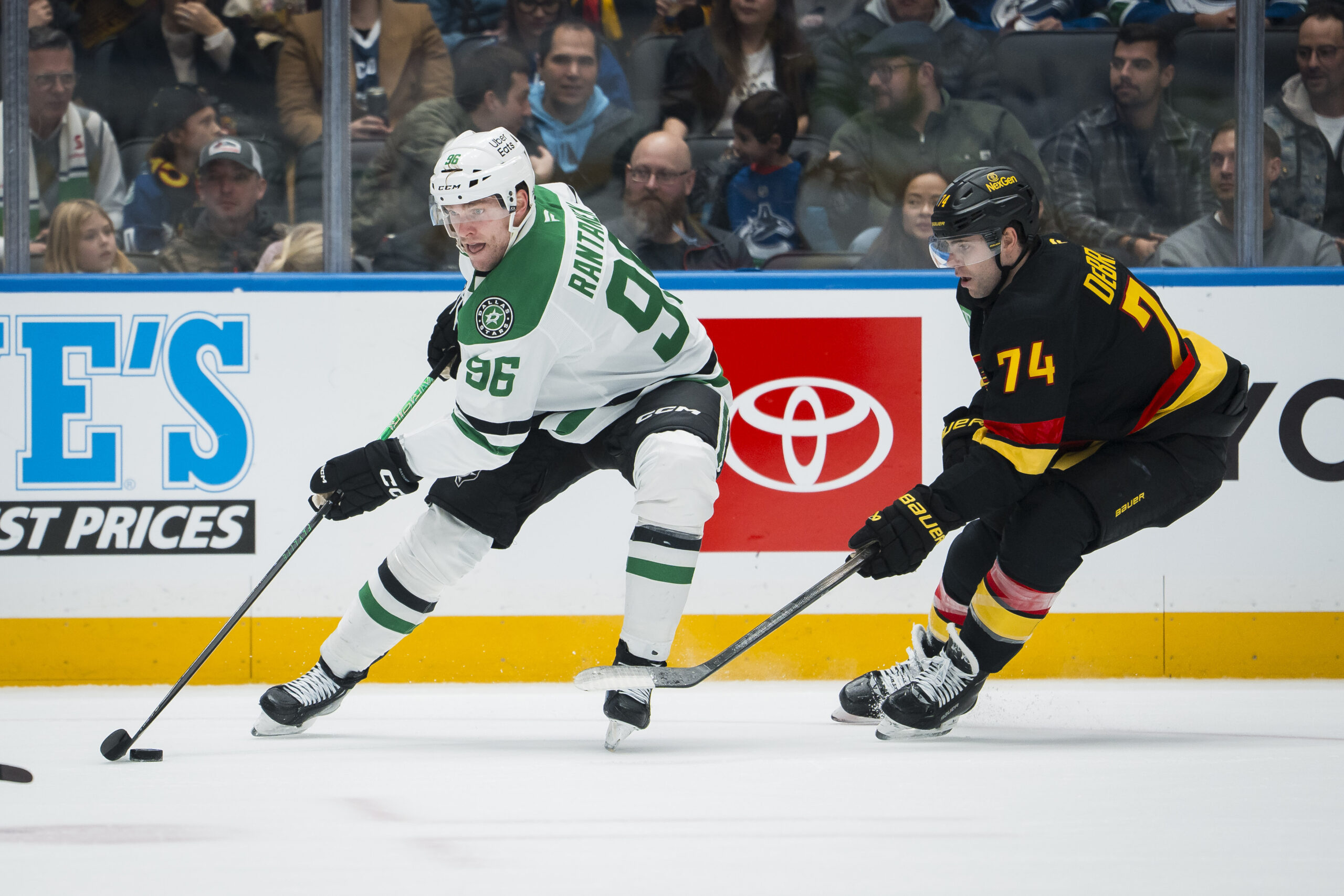 Nov 20, 2025; Vancouver, British Columbia, CAN; Dallas Stars forward Mikko Rantanen (96) drives past Vancouver Canucks forward Jake DeBrusk (74) in the first period at Rogers Arena. Mandatory Credit: Bob Frid-Imagn Images