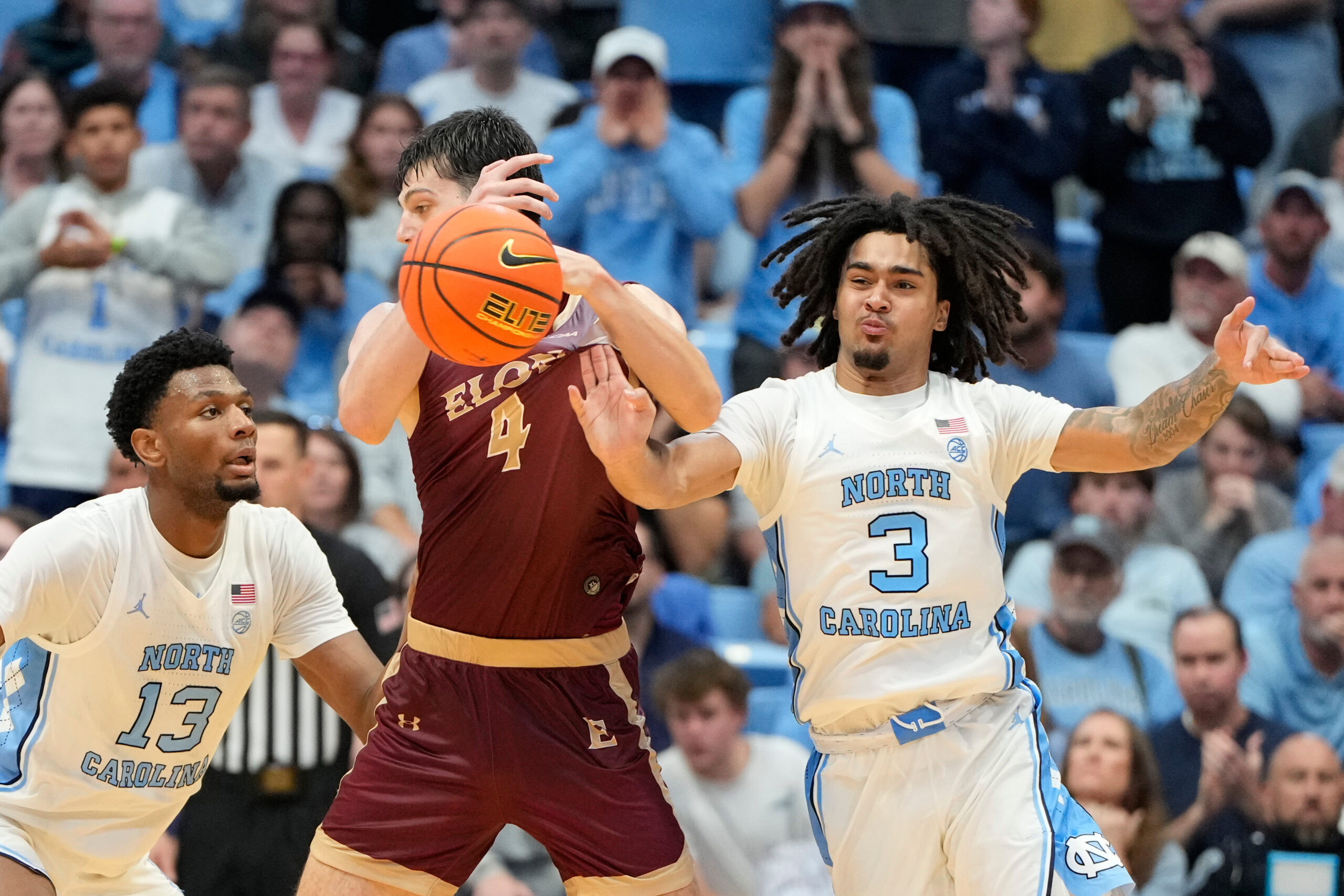 Nov 4, 2024; Chapel Hill, North Carolina, USA; North Carolina Tar Heels guard Elliot Cadeau (3) strips the ball from Elon Phoenix forward Sam Sherry (4) as forward Jalen Washington (13) helps defend in the second half at Dean E. Smith Center. Mandatory Credit: Bob Donnan-Imagn Images
