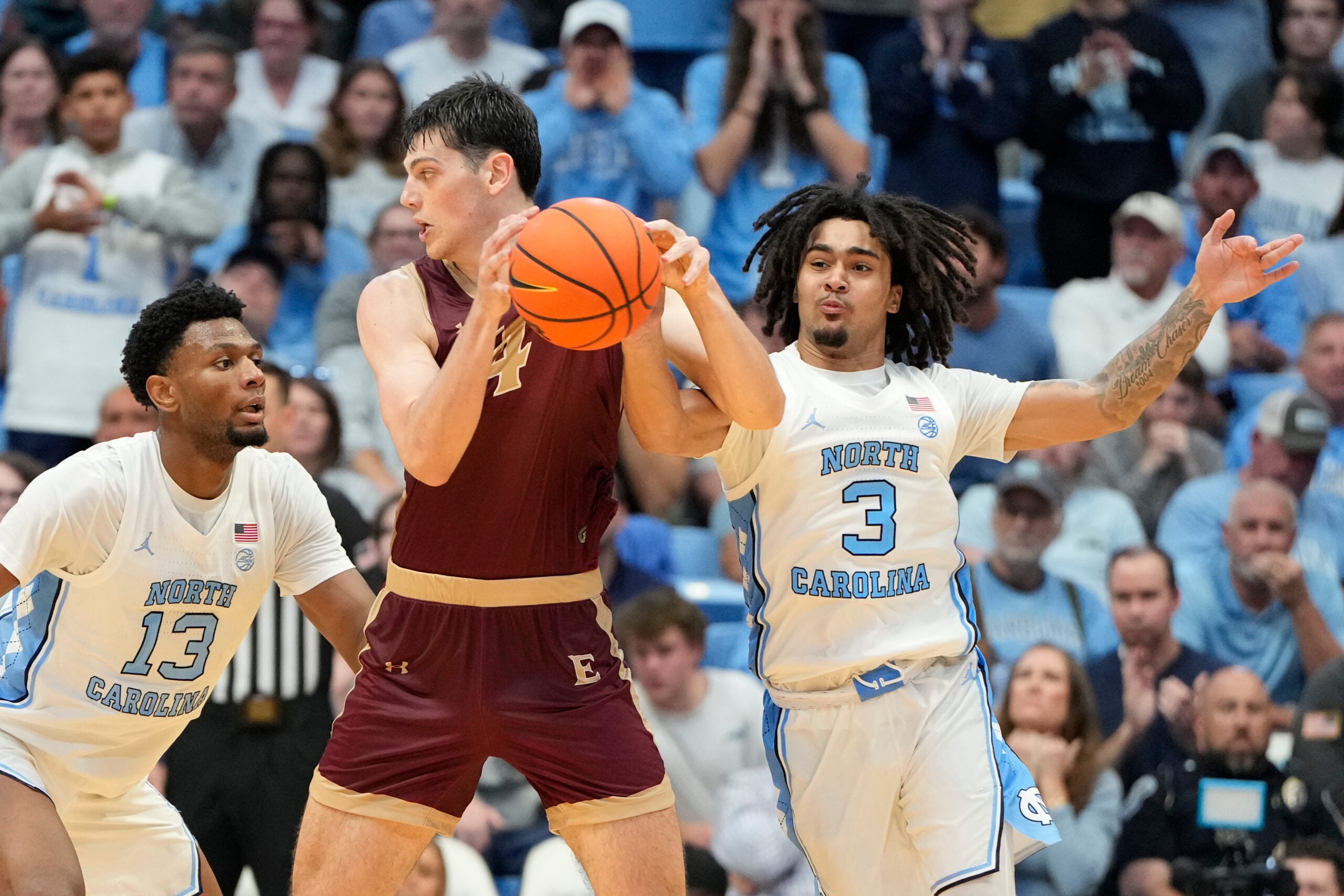 Nov 4, 2024; Chapel Hill, North Carolina, USA;  North Carolina Tar Heels guard Elliot Cadeau (3) strips the ball from Elon Phoenix forward Sam Sherry (4) as forward Jalen Washington (13) helps defend in the second half at Dean E. Smith Center. Mandatory Credit: Bob Donnan-Imagn Images