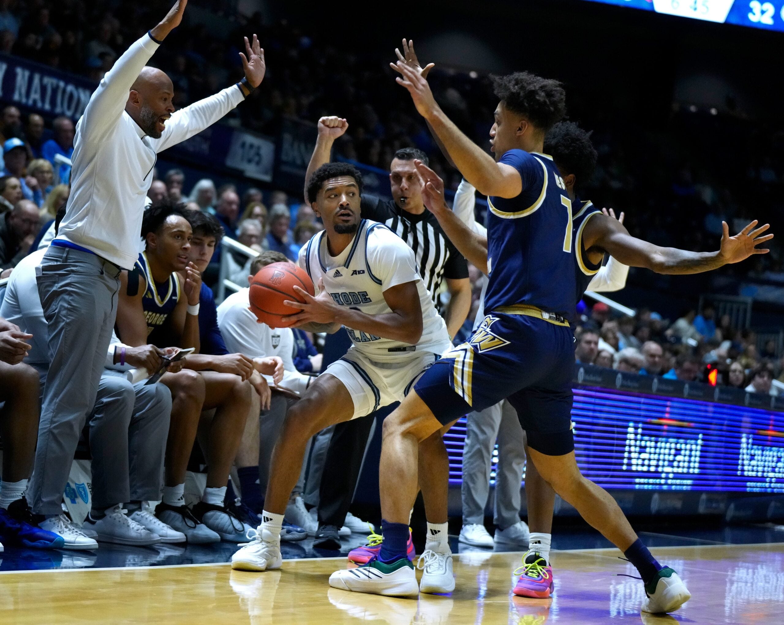 Jamarques Lawrence of URI looks for a way out of the double defense of Dayan Nessah and Christian Jones of George Washington.