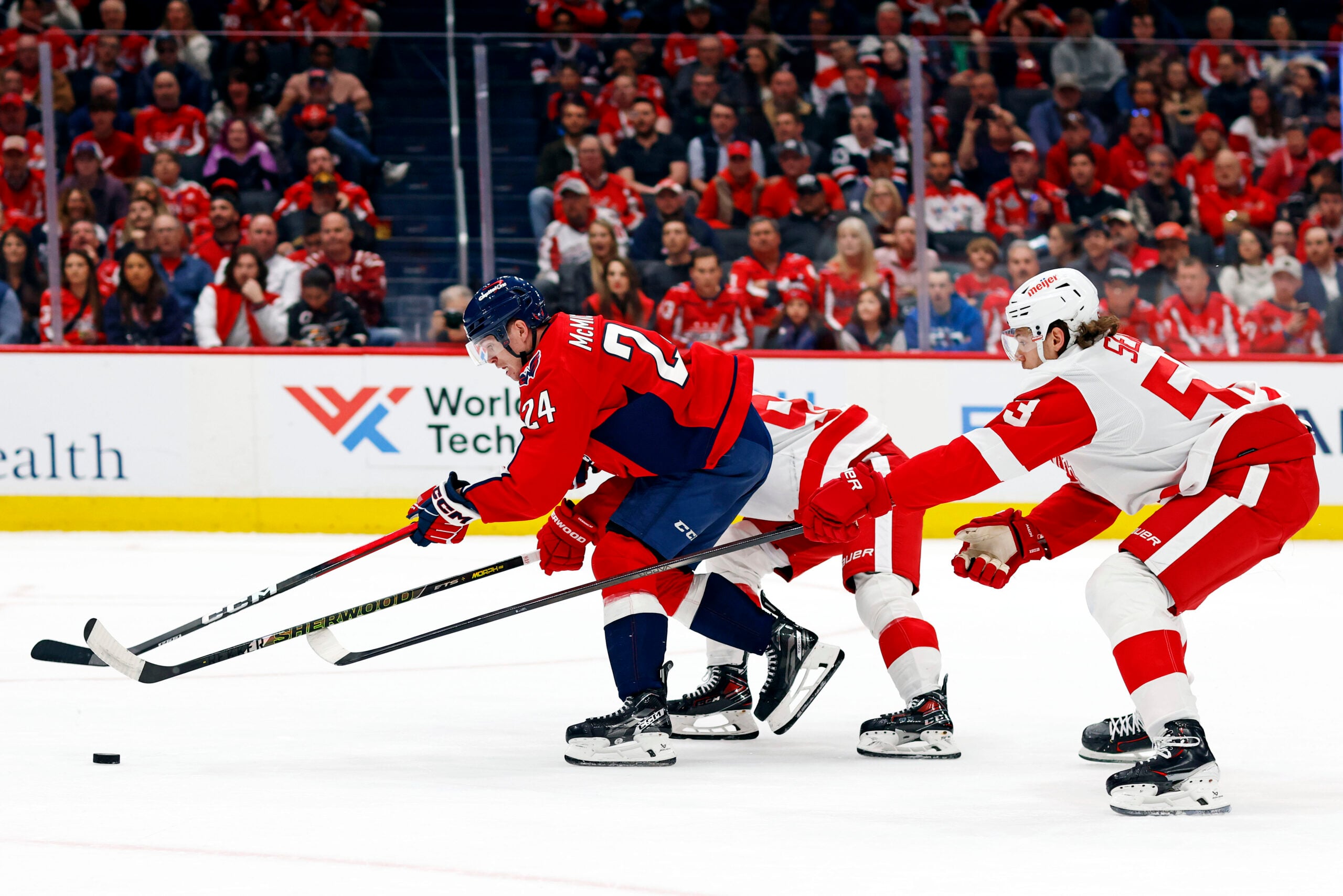 Mar 18, 2025; Washington, District of Columbia, USA; Washington Capitals center Connor McMichael (24) moves the puck against Detroit Red Wings defenseman Moritz Seider (53) during the first period at Capital One Arena. Mandatory Credit: Peter Casey-Imagn Images