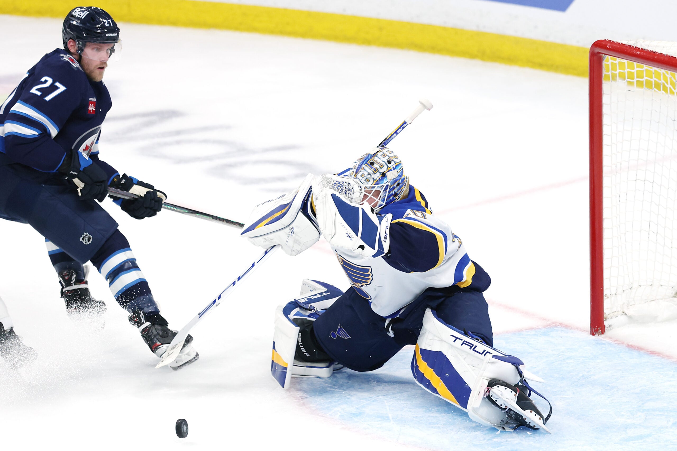 May 4, 2025; Winnipeg, Manitoba, CAN; St. Louis Blues goaltender Jordan Binnington (50) blocks a shot by Winnipeg Jets left wing Nikolaj Ehlers (27) in first overtime in game seven of the first round of the 2025 Stanley Cup Playoffs at Canada Life Centre. Mandatory Credit: James Carey Lauder-Imagn Images