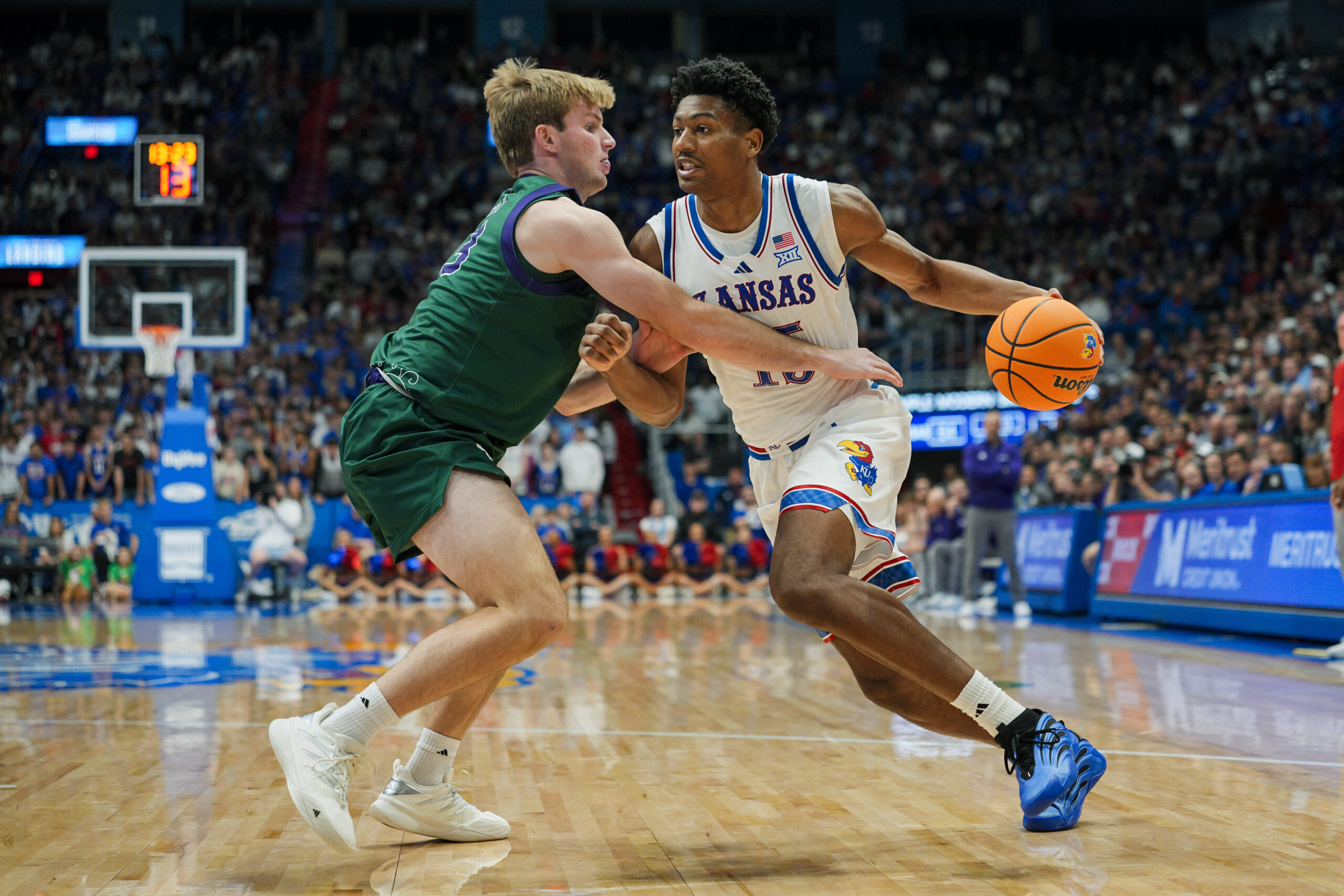 Nov 3, 2025; Lawrence, Kansas, USA; Kansas Jayhawks forward Bryson Tiller (15) drives against Green Bay Phoenix guard Keegan van Kauwenberg (3) during the second half at Allen Fieldhouse. Mandatory Credit: Jay Biggerstaff-Imagn Images