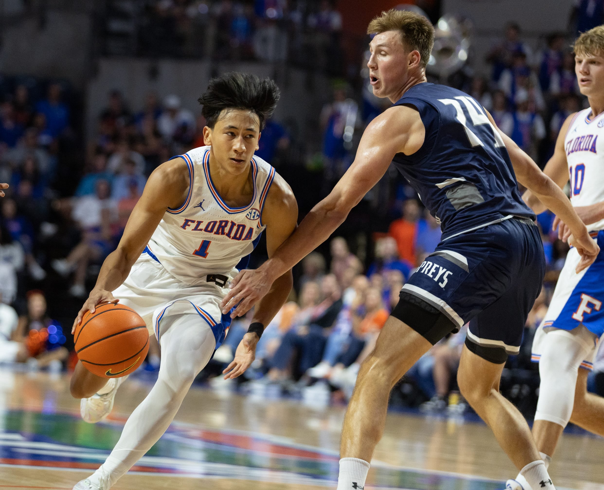 Florida guard Xaivian Lee (1) drives against North Florida forward Nestor Dyachok (24) during the second half of an NCAA basketball game at Steven C. O'Connel Center Exactech Areana in Gainesville, FL on Thursday, November 6, 2025. [Alan Youngblood/Gainesville Sun]