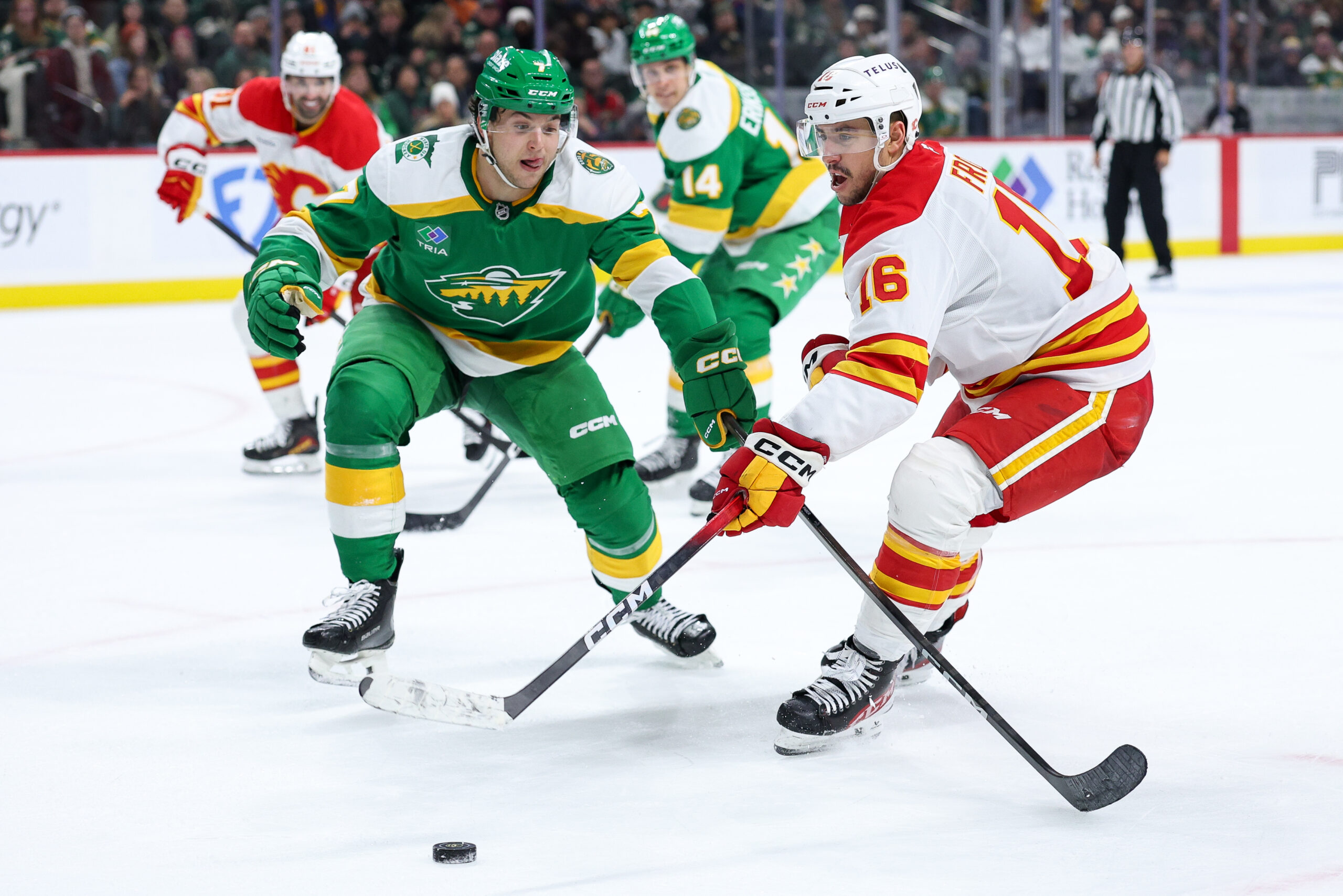 Nov 9, 2025; Saint Paul, Minnesota, USA; Calgary Flames center Morgan Frost (16) and Minnesota Wild defenseman Brock Faber (7) compete for the puck during the third period at Grand Casino Arena. Mandatory Credit: Matt Krohn-Imagn Images