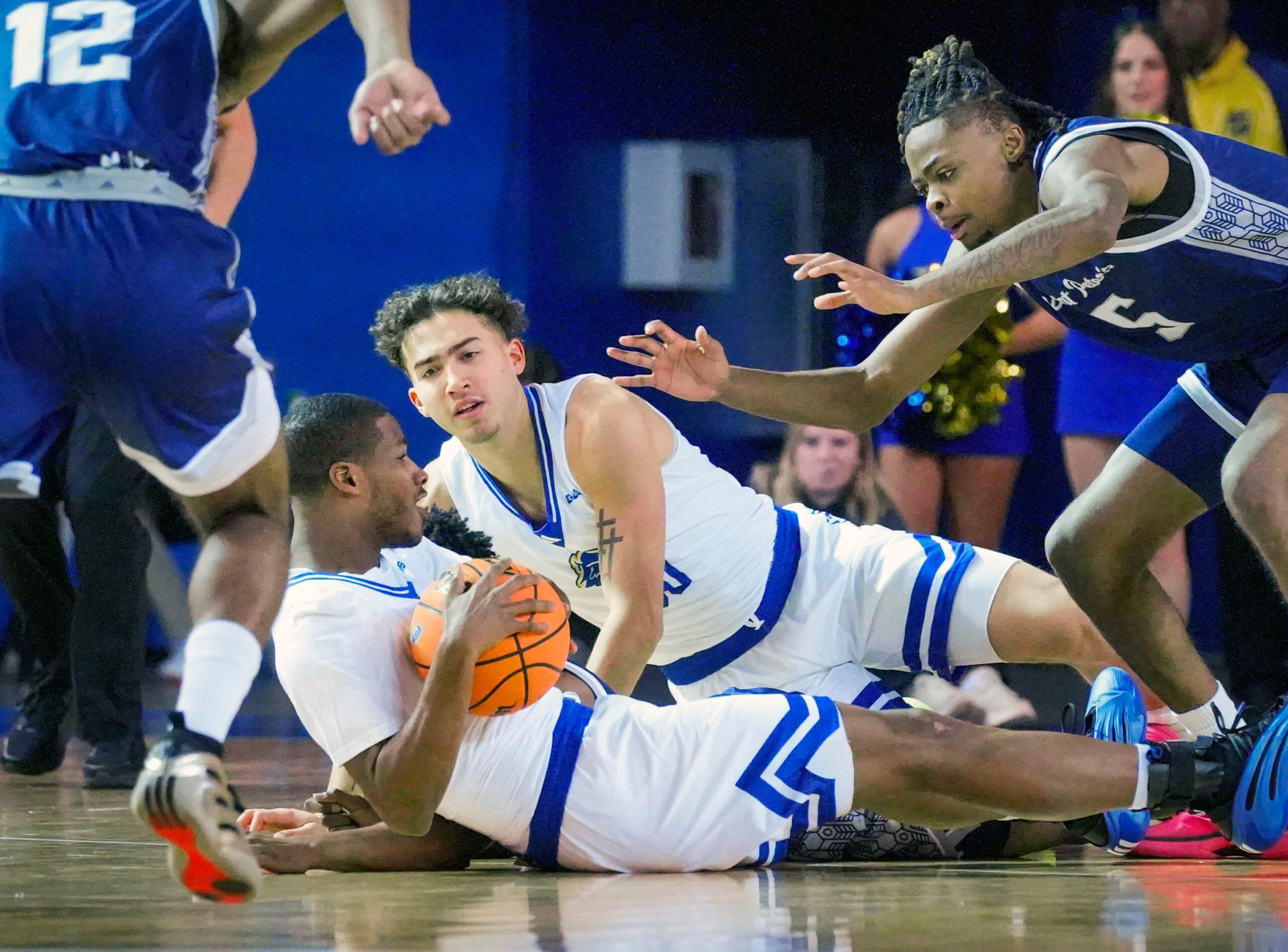 Delaware’s Jameel Brown (bottom) and Christian Bliss move for a loose ball ahead of Saint Peter’s Jahki Gupton in the first half of the Blue Hens’ 81-70 win at the Bob Carpenter Center, Nov. 18, 2025.