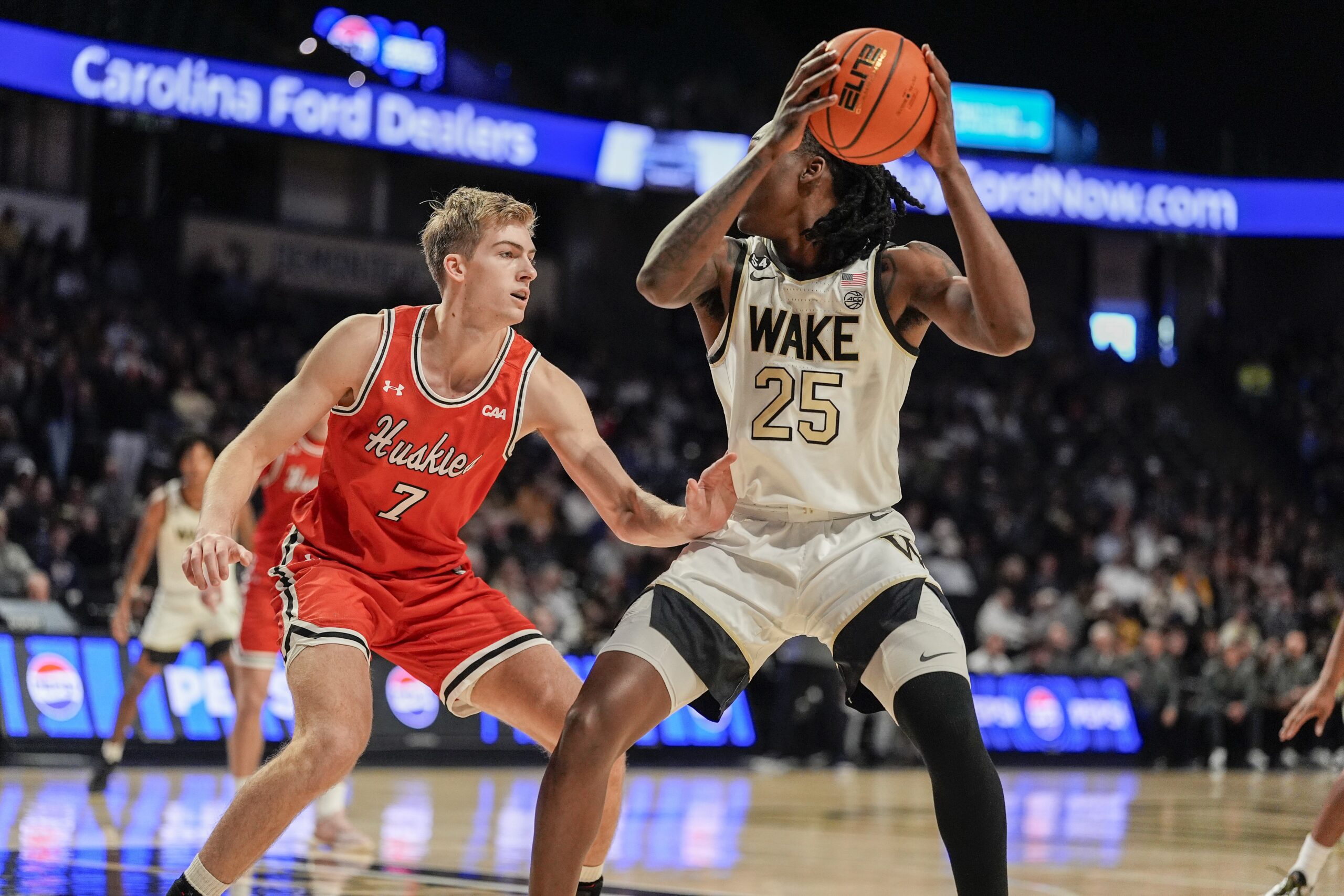 Nov 28, 2025; Winston-Salem, North Carolina, USA; Wake Forest Demon Deacons forward Tre'Von Spillers (25) handles the ball against Northeastern Huskies forward Youri Fritz (7) during the first half at Lawrence Joel Veterans Memorial Coliseum. Mandatory Credit: Jim Dedmon-Imagn Images
