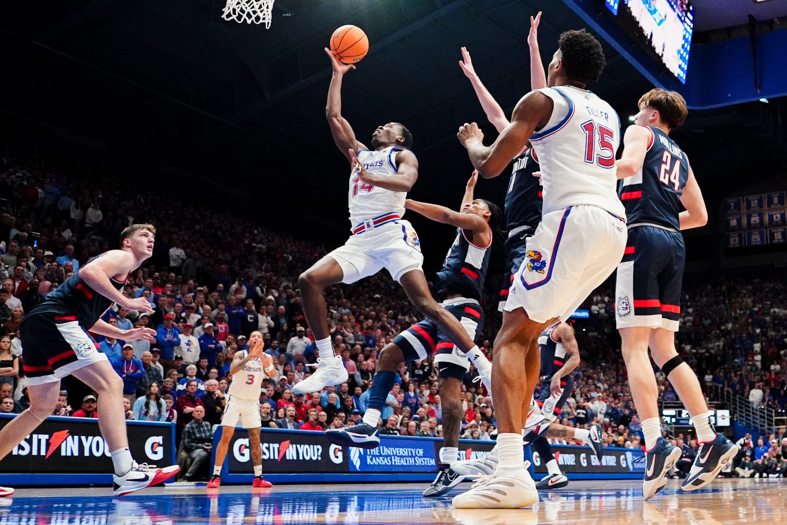 Dec 2, 2025; Lawrence, Kansas, USA; Kansas Jayhawks guard Melvin Council Jr. (14) shoots as UConn Huskies guard Braylon Mullins (24) looks on during the second half of the game at Allen Fieldhouse. Mandatory Credit: Denny Medley-Imagn Images