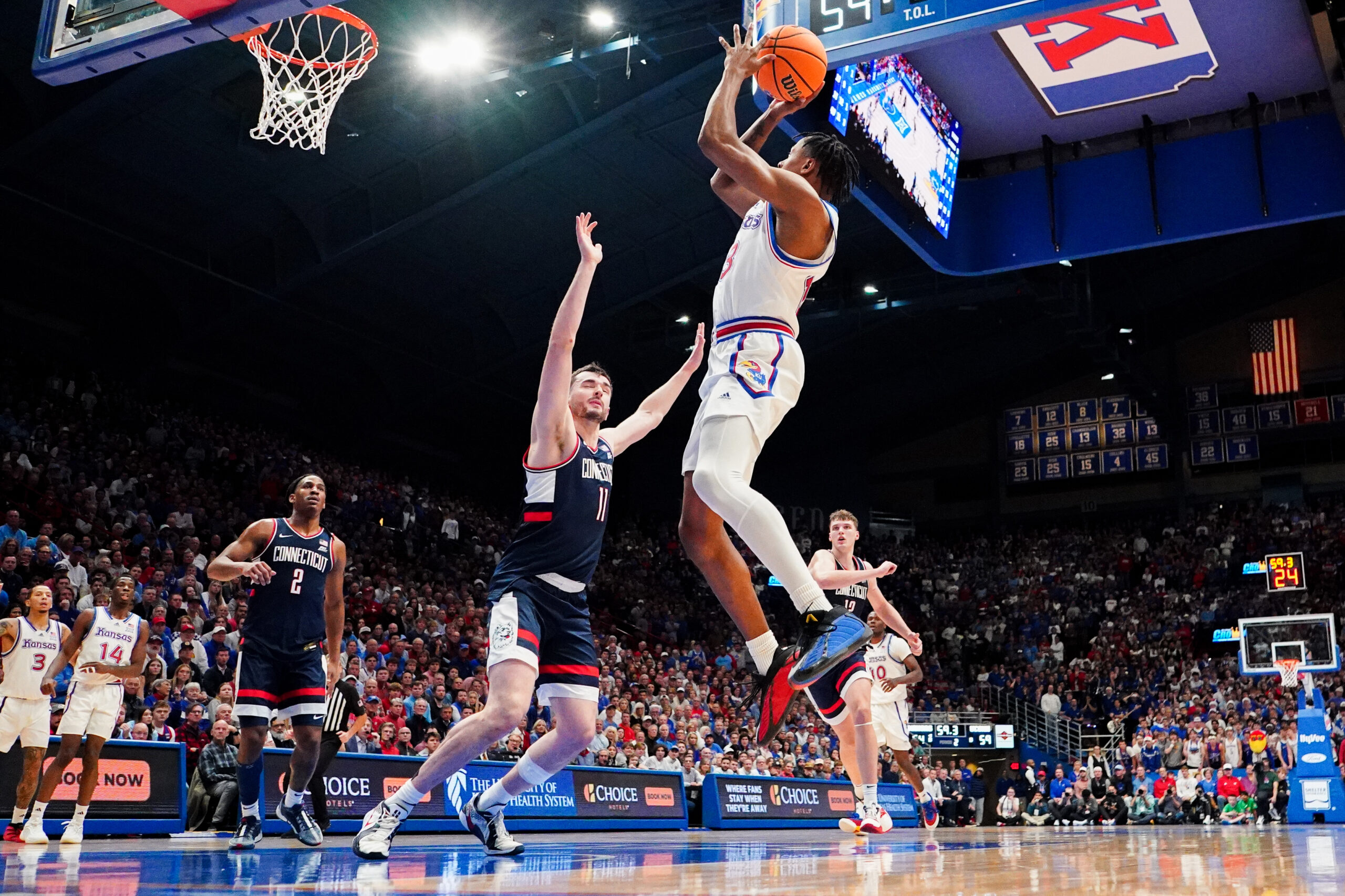 Dec 2, 2025; Lawrence, Kansas, USA; Kansas Jayhawks guard Elmarko Jackson (13) shoots as UConn Huskies forward Alex Karaban (11) defends during the second half of the game at Allen Fieldhouse. Mandatory Credit: Denny Medley-Imagn Images