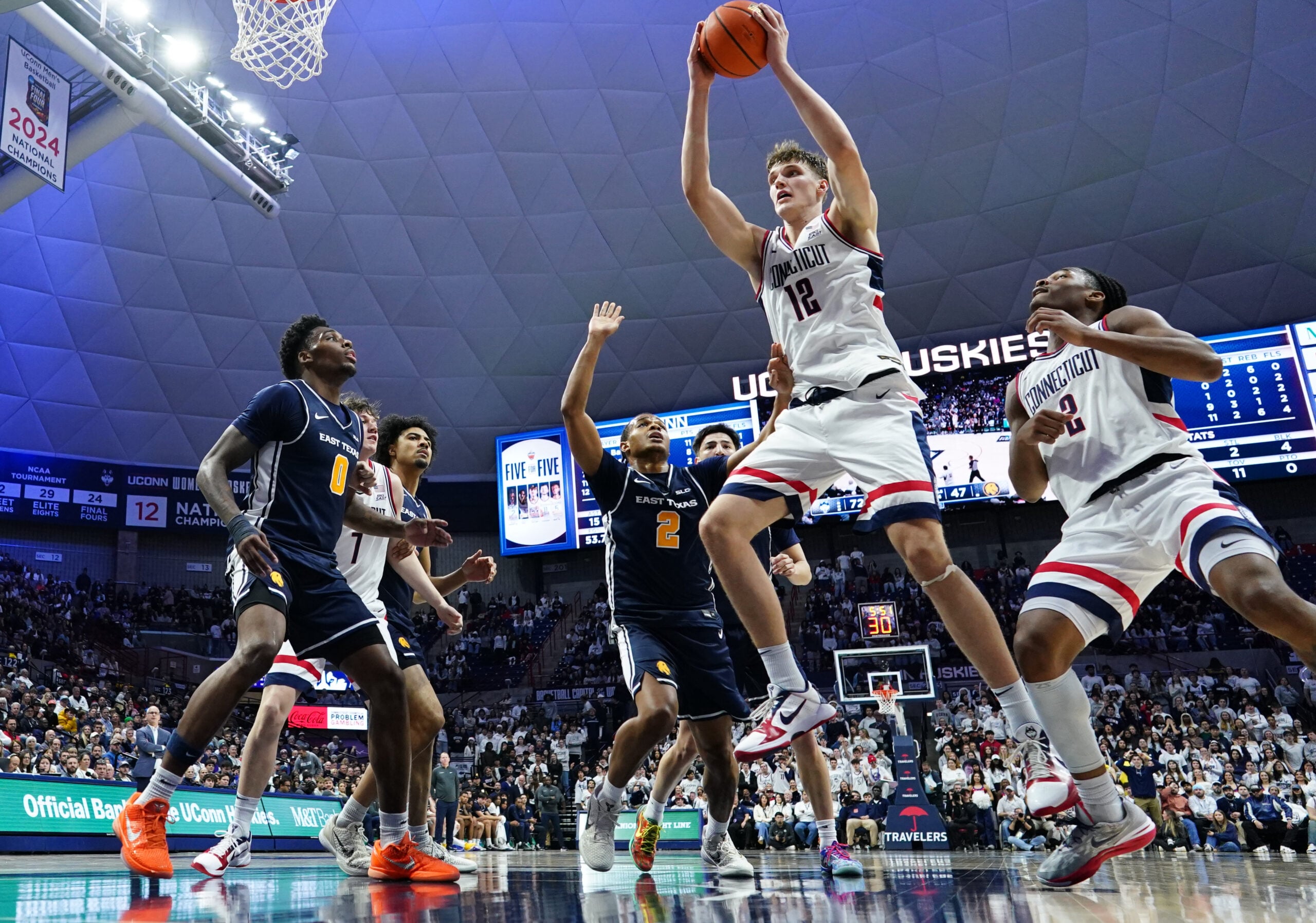 Dec 5, 2025; Storrs, Connecticut, USA; UConn Huskies center Eric Reibe (12) grabs the rebound against the East Texas A&M Lions in the second half at Harry A. Gampel Pavilion. Mandatory Credit: David Butler II-Imagn Images