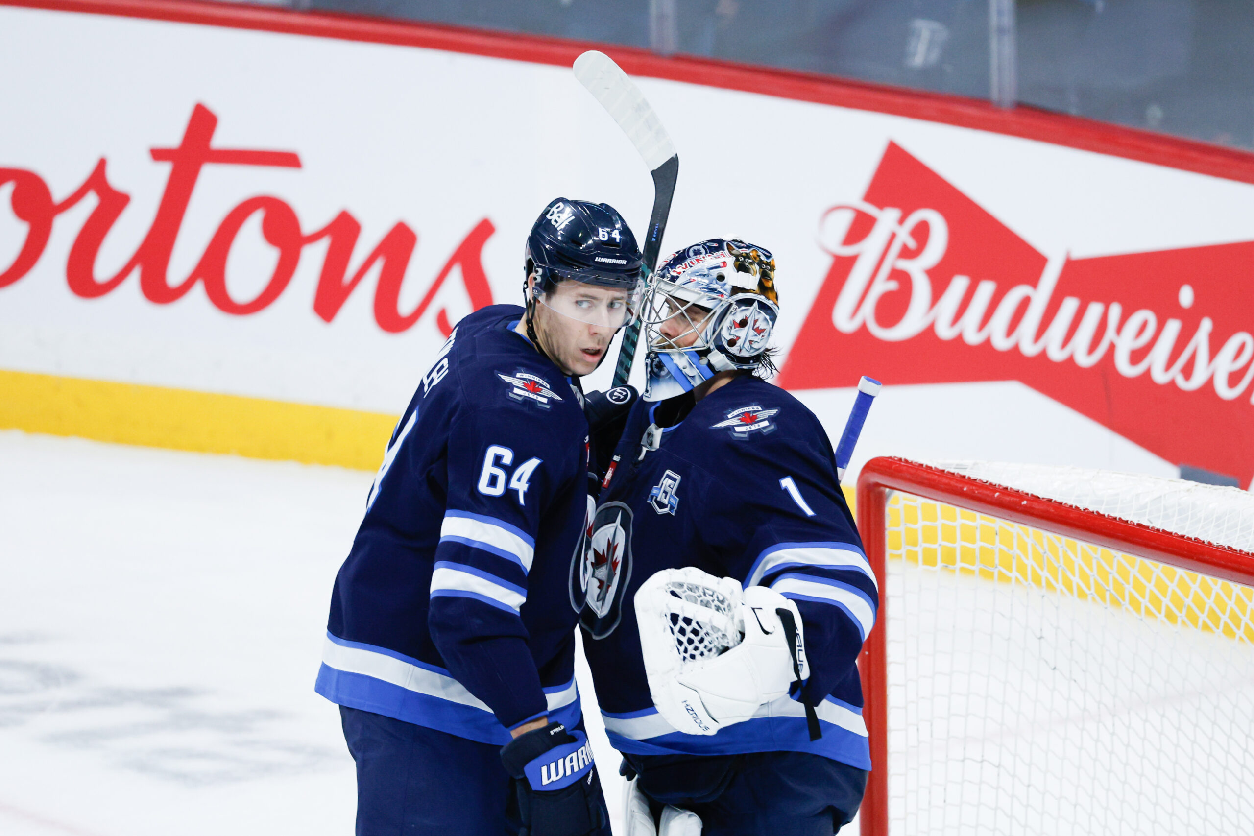 Dec 5, 2025; Winnipeg, Manitoba, CAN; Winnipeg Jets goalie Eric Comrie (1) is congratulated by defenseman Logan Stanley (64) on his win against the Buffalo Sabres during the third period at Canada Life Centre. Mandatory Credit: Terrence Lee-Imagn Images