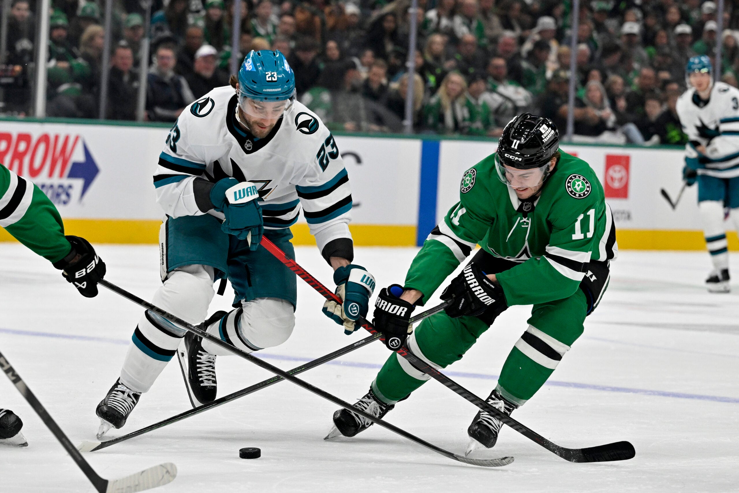 Dec 5, 2025; Dallas, Texas, USA; San Jose Sharks center Barclay Goodrow (23) and Dallas Stars right wing Nathan Bastian (11) battle for control of the puck during the third period at the American Airlines Center. Mandatory Credit: Jerome Miron-Imagn Images