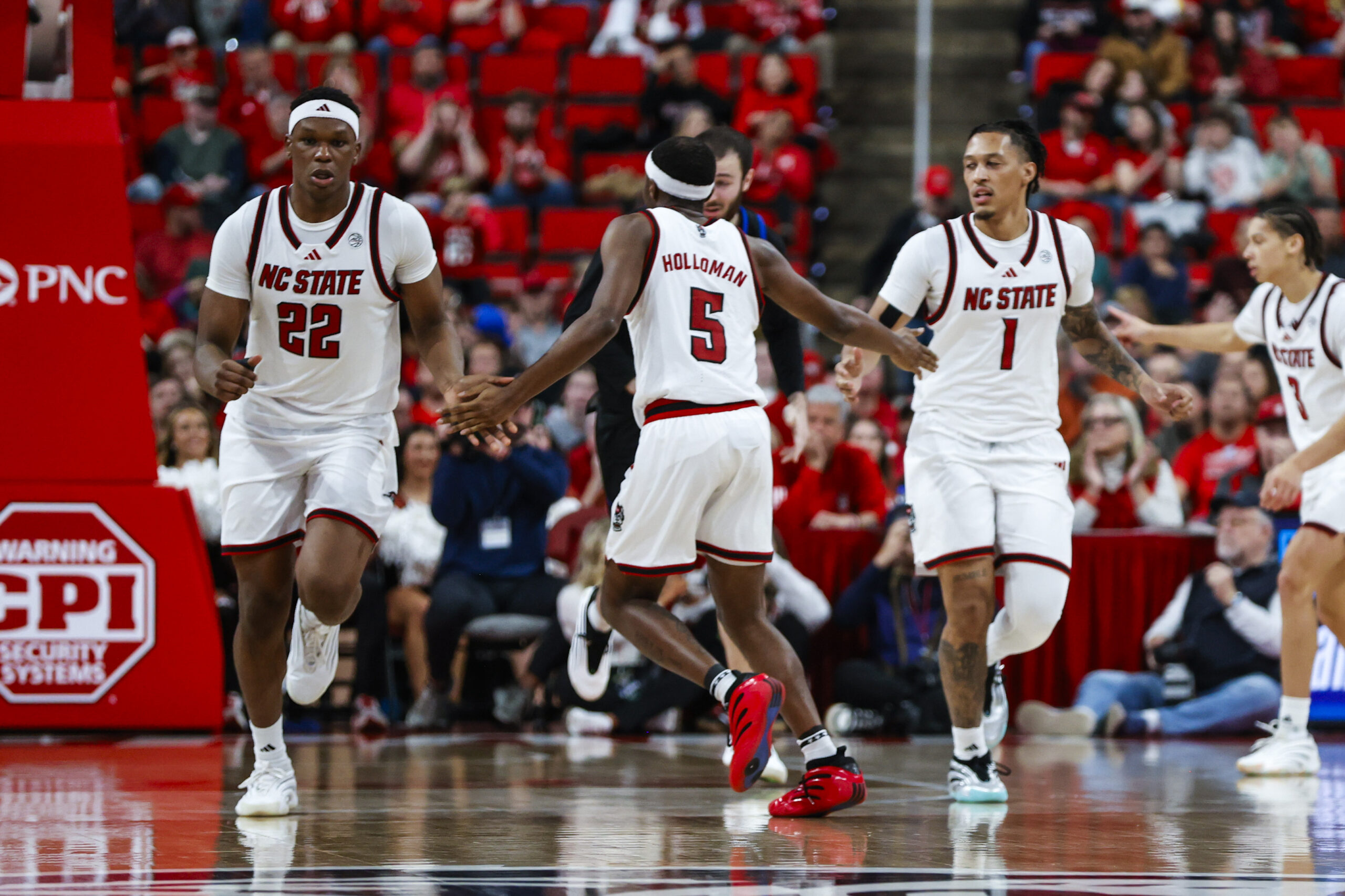Dec 6, 2025; Raleigh, North Carolina, USA; NC State Wolfpack guard Tre Holloman (5) high fives forward Ven-Allen Lubin (22) and forward Darrion Williams (1) during the second half of the game against UNC Asheville Bulldogs at Lenovo Center. Mandatory Credit: Jaylynn Nash-Imagn Images