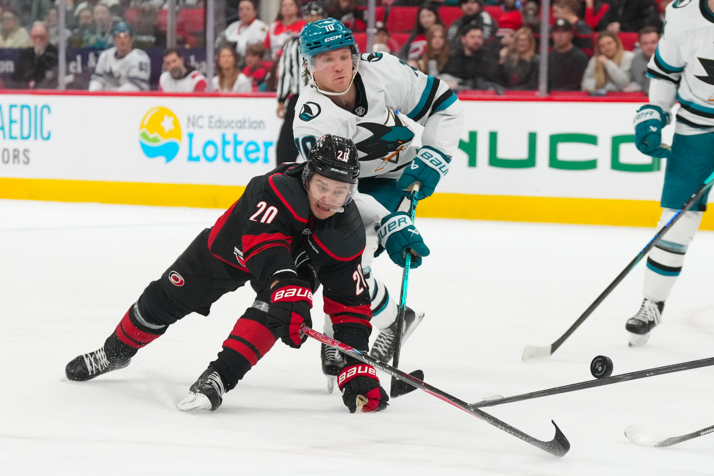 Dec 7, 2025; Raleigh, North Carolina, USA; Carolina Hurricanes center Sebastian Aho (20) and San Jose Sharks center Ty Dellandrea (10) battle over the puck during the third period at Lenovo Center. Mandatory Credit: James Guillory-Imagn Images