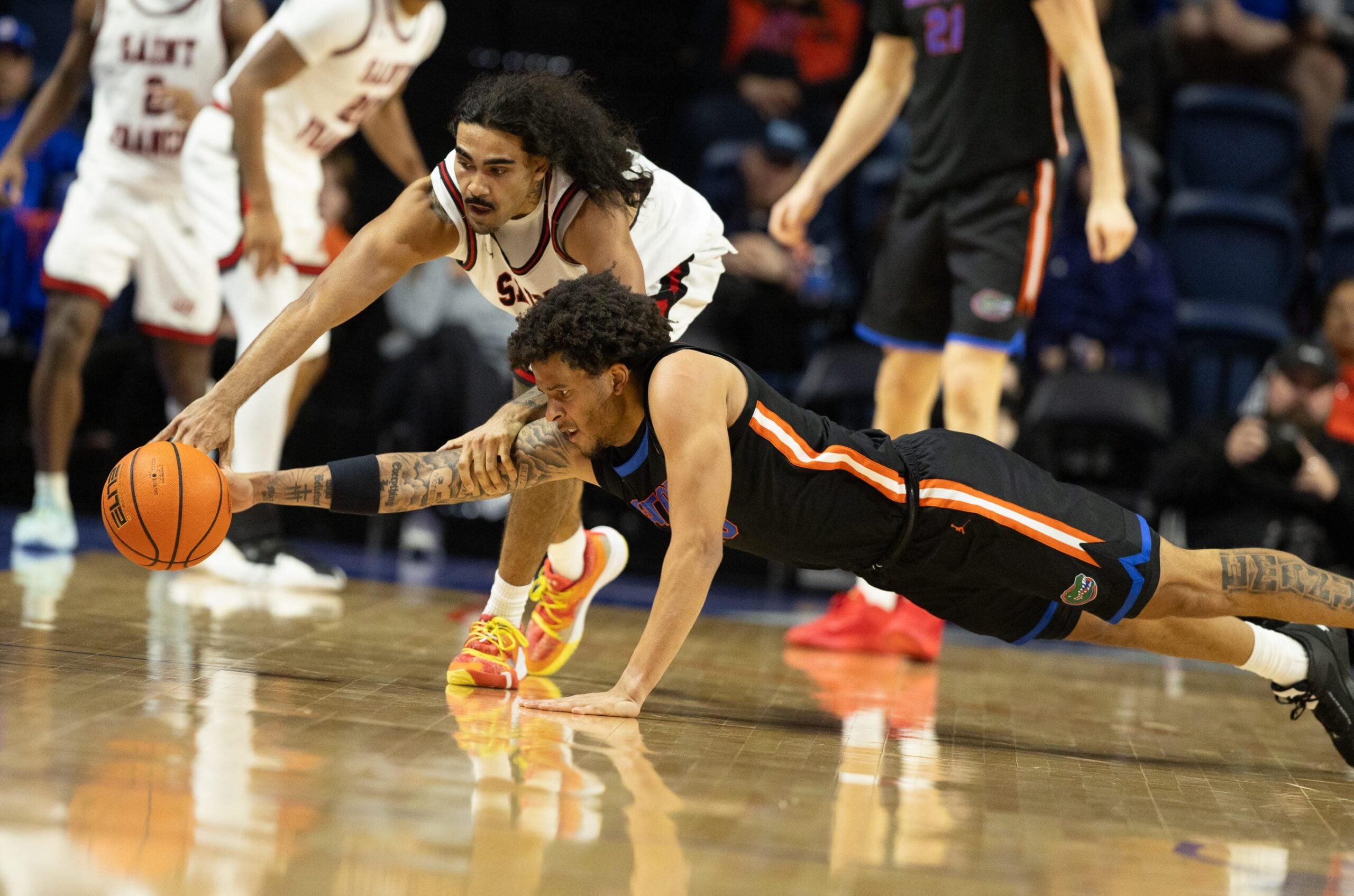 Saint Francis guard Skylar Wicks (8) and Florida guard Isaiah Brown (20) dive during the second half of an NCAA mens basketball game at Steven C. O'Connell Center Exactek arena in Gainesville, FL on Wednesday, December 17, 2025. Florida won 76-51[Alan Youngblood/Gainesville Sun]