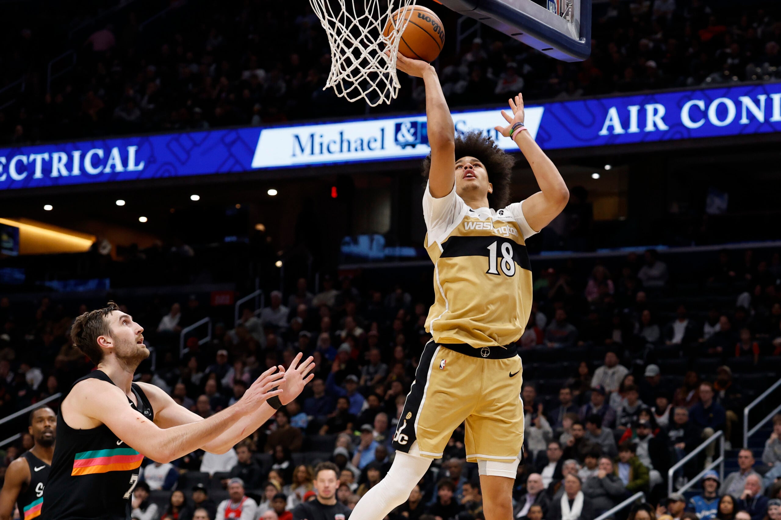 Dec 21, 2025; Washington, District of Columbia, USA; Washington Wizards forward Kyshawn George (18) shoots the ball as San Antonio Spurs center Luke Kornet (7) defends in the second half at Capital One Arena. Mandatory Credit: Geoff Burke-Imagn Images