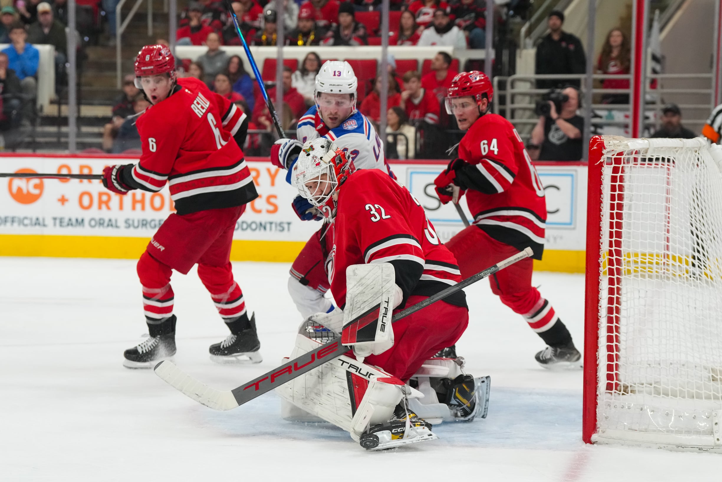 Dec 29, 2025; Raleigh, North Carolina, USA; Carolina Hurricanes goaltender Brandon Bussi (32) stops the shot next to New York Rangers left wing Alexis Lafreniere (13) during the second period at Lenovo Center. Mandatory Credit: James Guillory-Imagn Images