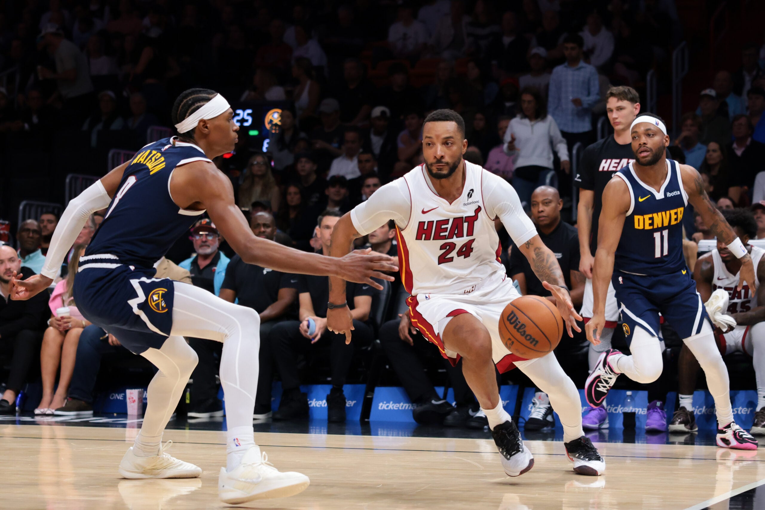 Dec 29, 2025; Miami, Florida, USA; Miami Heat guard Norman Powell (24) drives to the basket against Denver Nuggets guard Bruce Brown (11) and guard Peyton Watson (8) during the third quarter at Kaseya Center. Mandatory Credit: Sam Navarro-Imagn Images