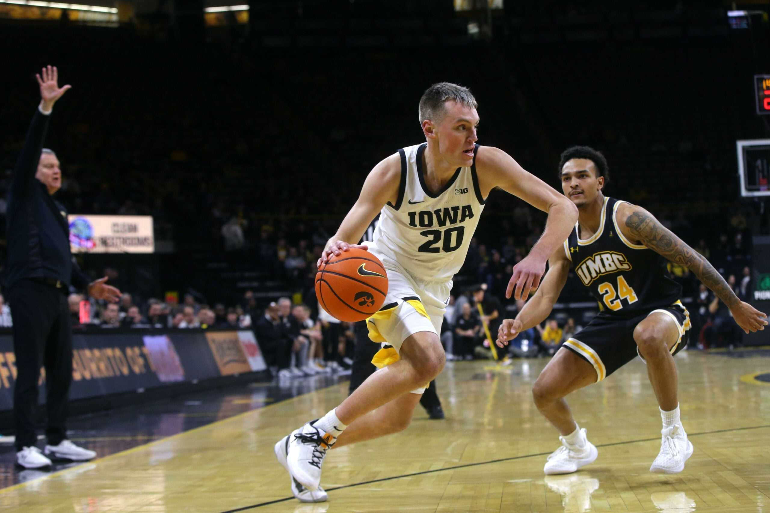 Iowa   s Payton Sandfort (20) drives toward the lane defended by UMBC's Marcus Banks Jr. (24) Wednesday, Dec. 20, 2023 at Carver-Hawkeye Arena in Iowa City, Iowa.