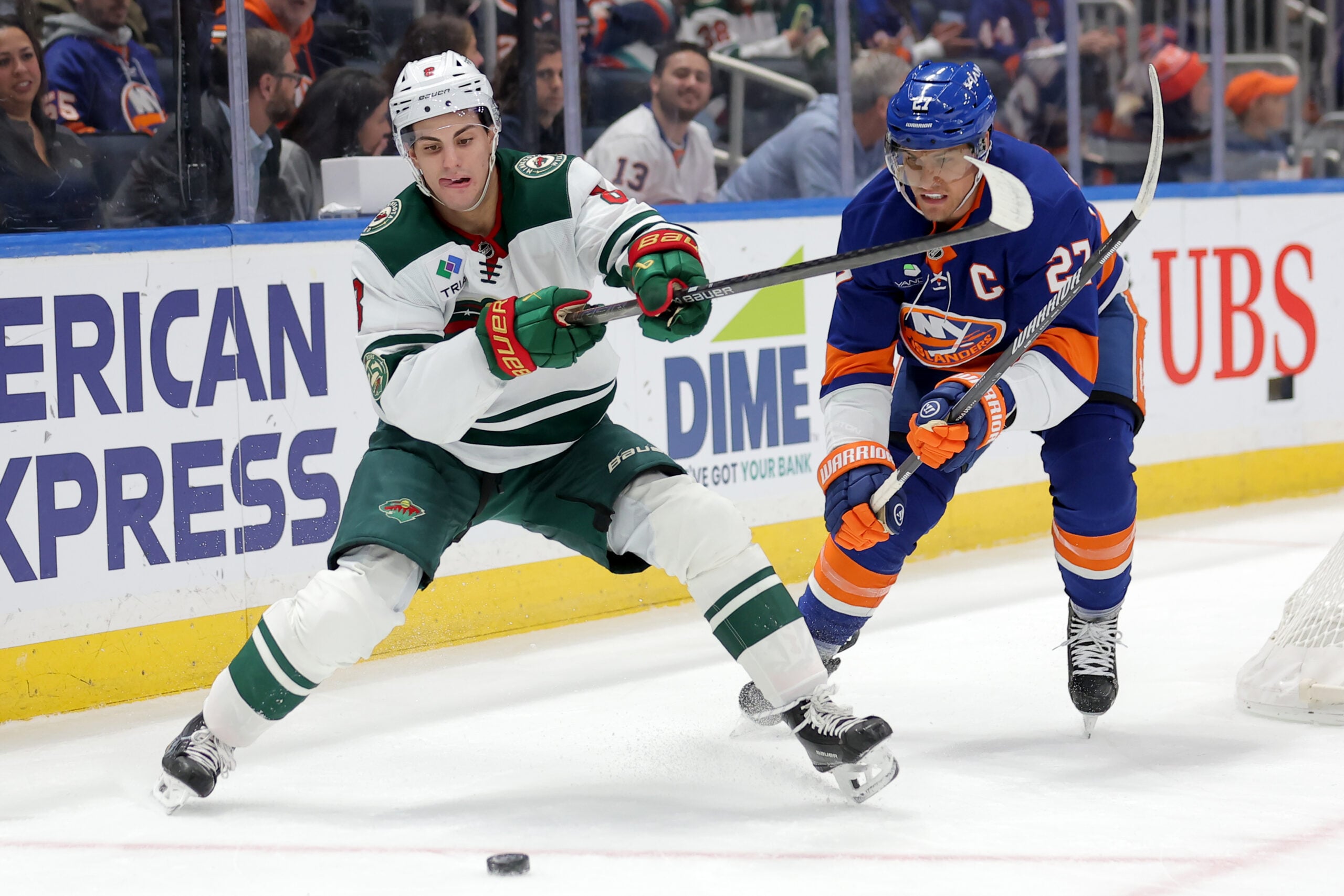 Nov 7, 2025; Elmont, New York, USA; Minnesota Wild defenseman Zeev Buium (8) fights for the puck against New York Islanders left wing Anders Lee (27) during the first period at UBS Arena. Mandatory Credit: Brad Penner-Imagn Images