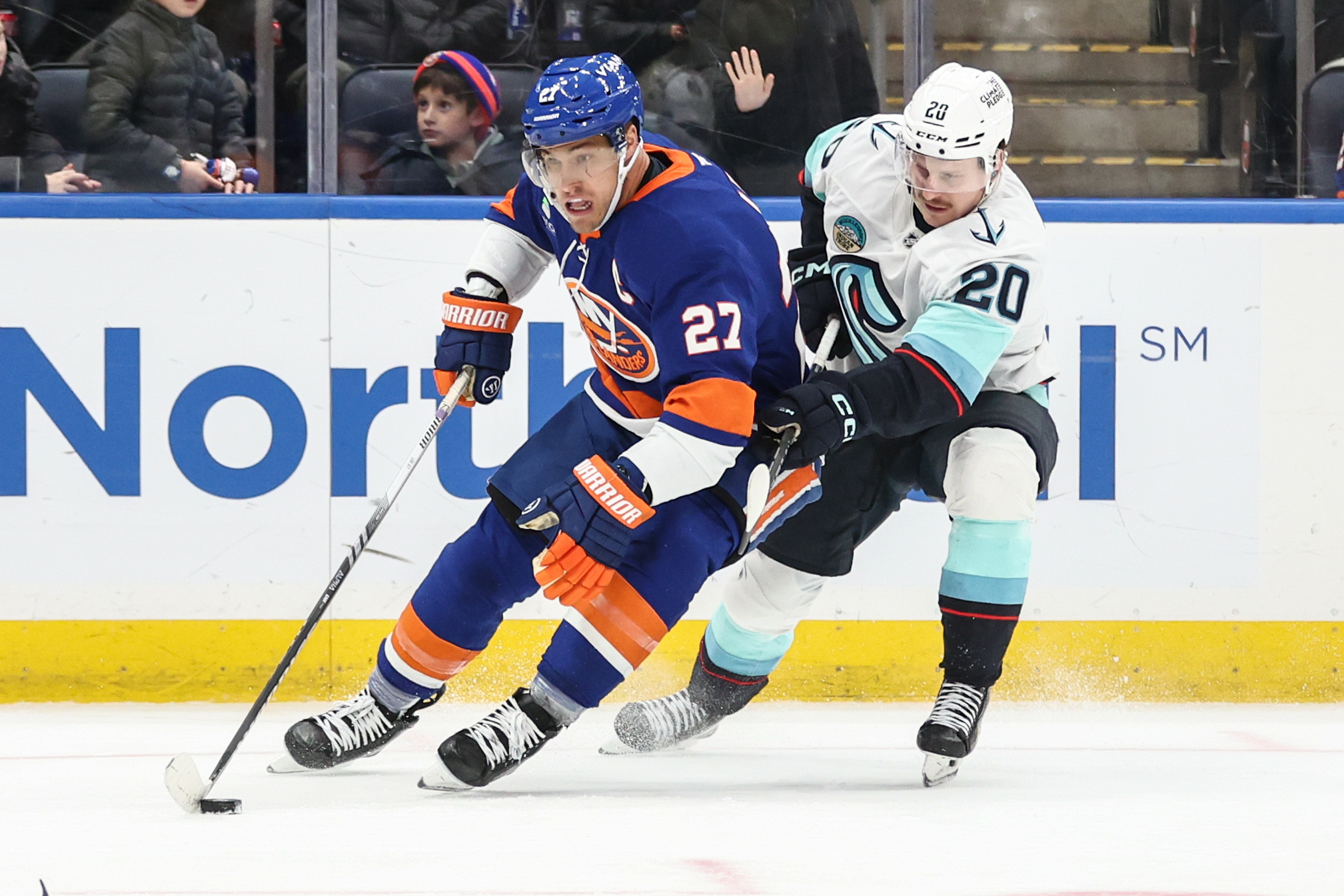 Nov 23, 2025; Elmont, New York, USA;  New York Islanders left wing Anders Lee (27) and Seattle Kraken right wing Eeli Tolvanen (20) battle for control of the puck in the third period at UBS Arena. Mandatory Credit: Wendell Cruz-Imagn Images