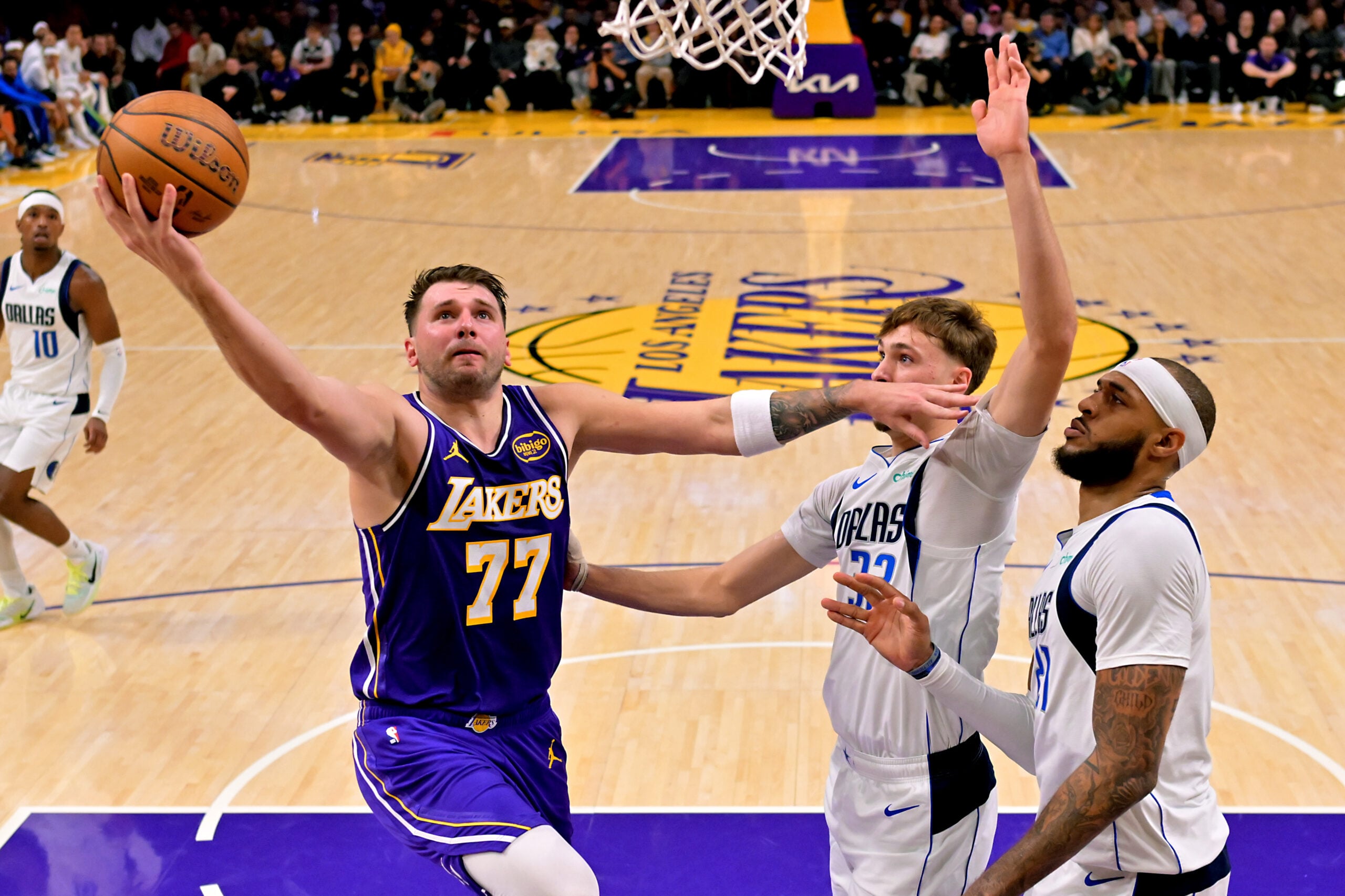 Nov 28, 2025; Los Angeles, California, USA;  Los Angeles Lakers guard Luka Doncic (77) drives past Dallas Mavericks forward Cooper Flagg (32) and forward Daniel Gafford (21) in the first half at Crypto.com Arena. Mandatory Credit: Jayne Kamin-Oncea-Imagn Images