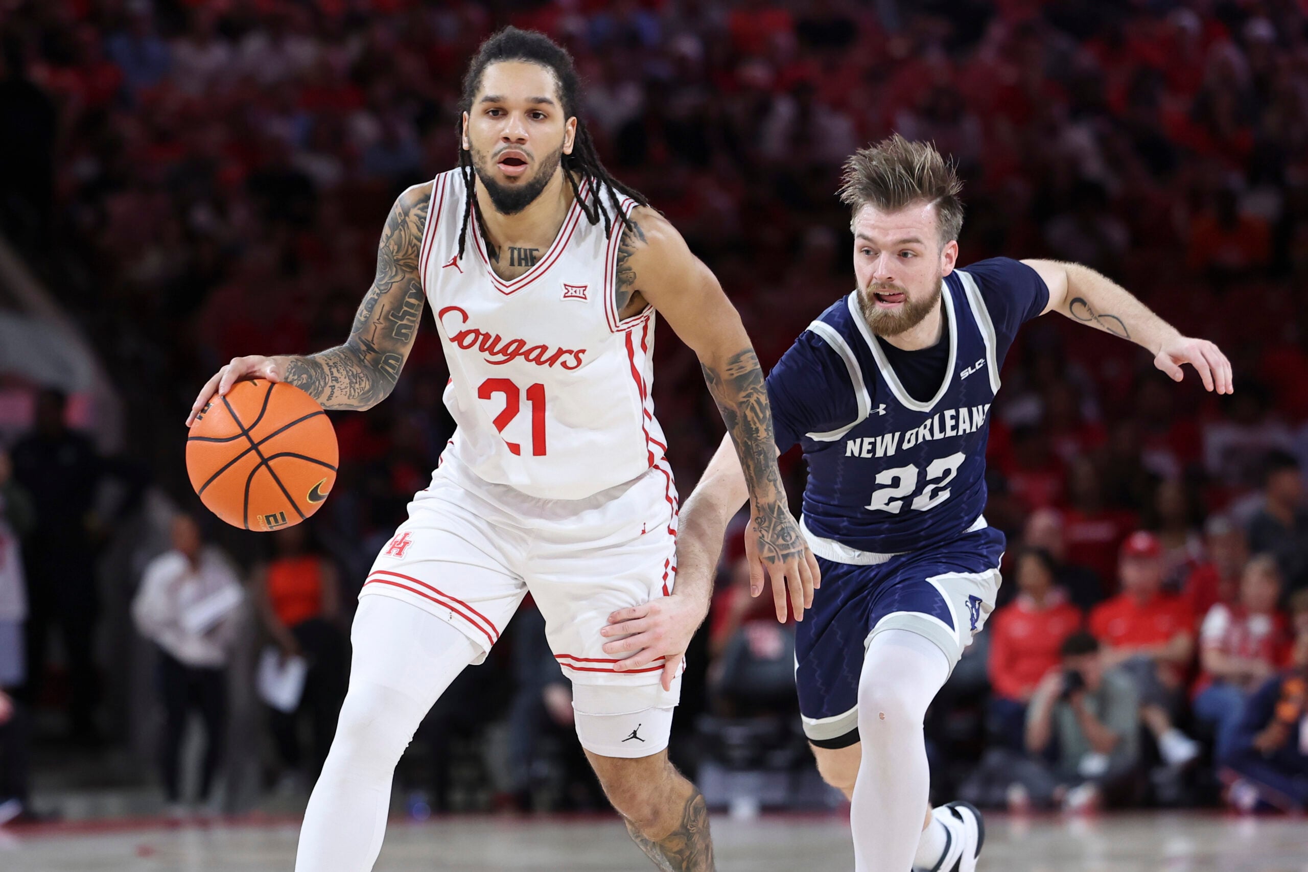 Dec 13, 2025; Houston, Texas, USA; Houston Cougars guard Emanuel Sharp (21) dribbles the ball as New Orleans Privateers guard Coleton Benson (22) defends during the first half at Fertitta Center. Mandatory Credit: Troy Taormina-Imagn Images