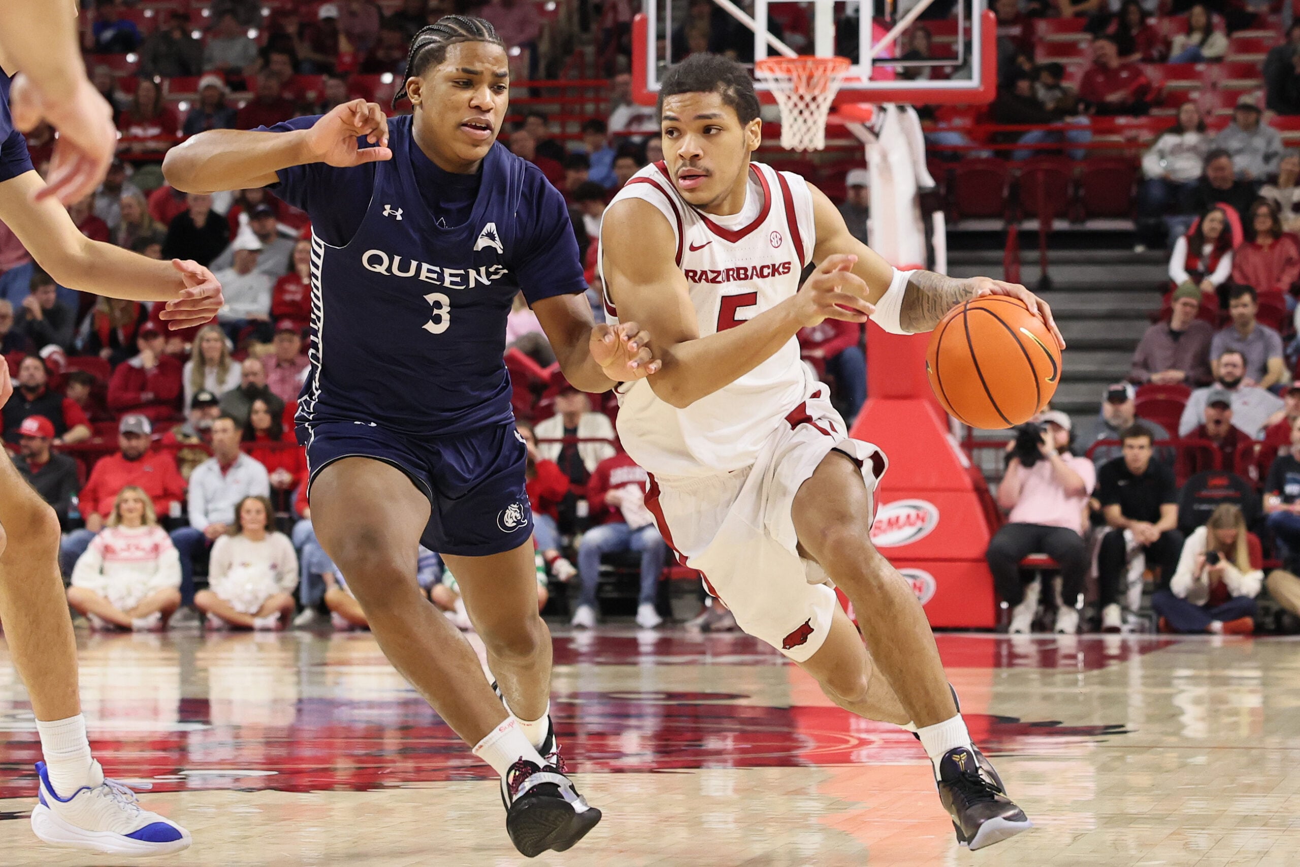 Dec 16, 2025; Fayetteville, Arkansas, USA; Arkansas Razorbacks guard Darius Acuff Jr (5) drives against Queens Royals Isaiah Henry (3) during the second half at Bud Walton Arena. Arkansas won 108-80. Mandatory Credit: Nelson Chenault-Imagn Images