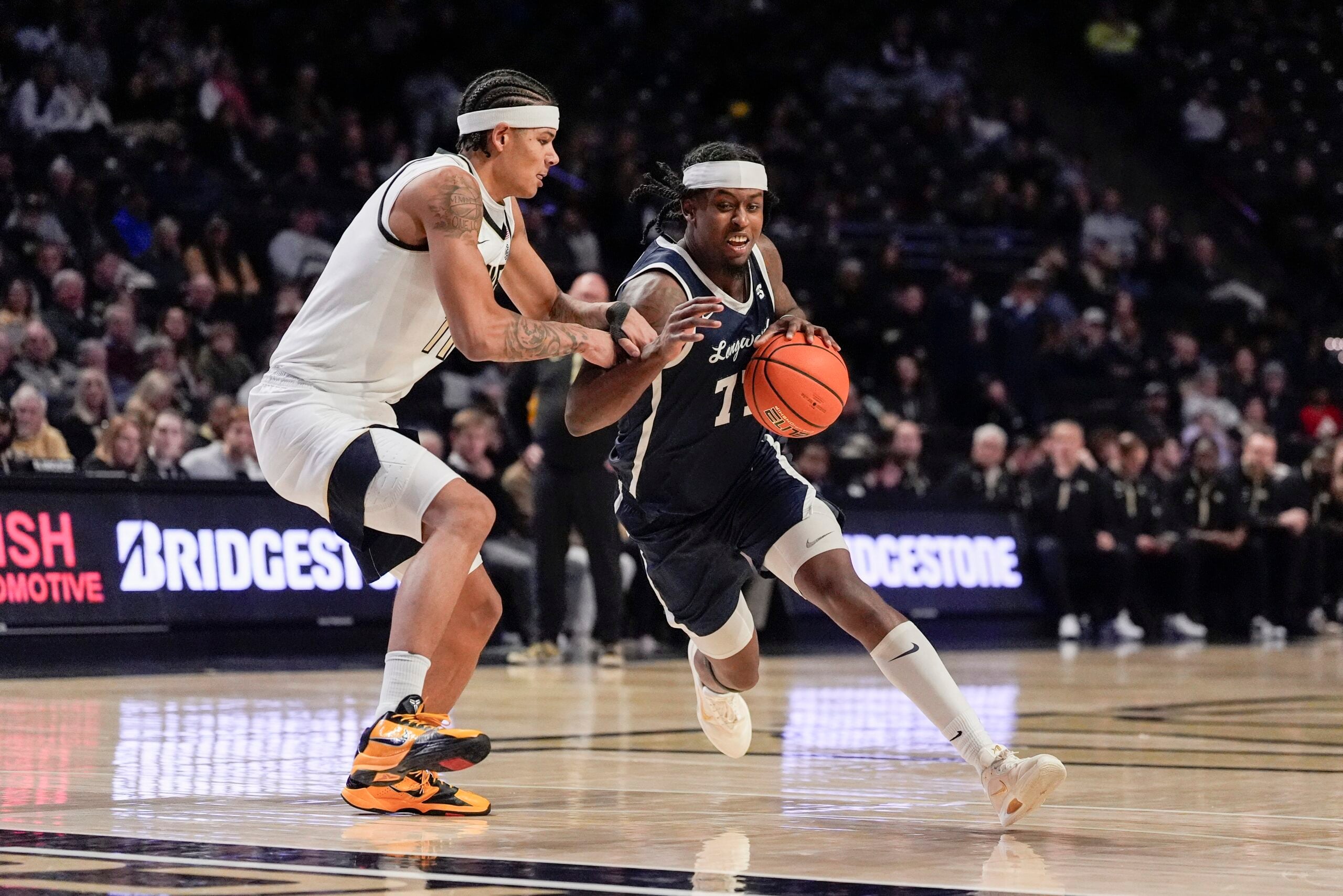 Dec 17, 2025; Winston-Salem, North Carolina, USA; Longwood Lancers forward Elijah Tucker (77) handles the ball against Wake Forest Demon Deacons forward Marqus Marion (11) during the second half at Lawrence Joel Veterans Memorial Coliseum. Mandatory Credit: Jim Dedmon-Imagn Images