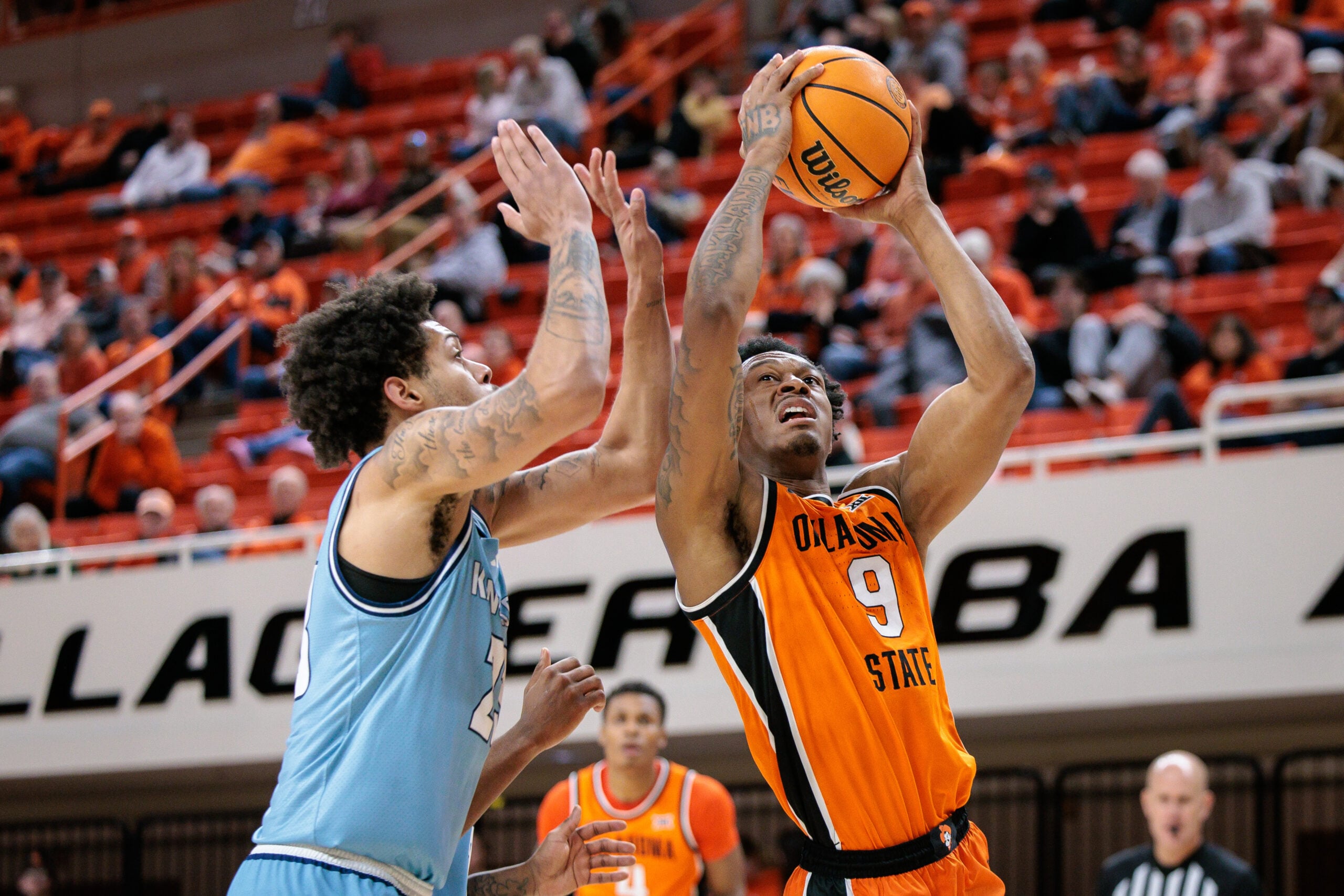 Dec 18, 2025; Stillwater, Oklahoma, USA; Oklahoma State Cowboys guard Anthony Roy (9) shoots the ball around Kansas City Roos forward Addarin Scott (23) during the second half at Gallagher-Iba Arena. Mandatory Credit: William Purnell-Imagn Images