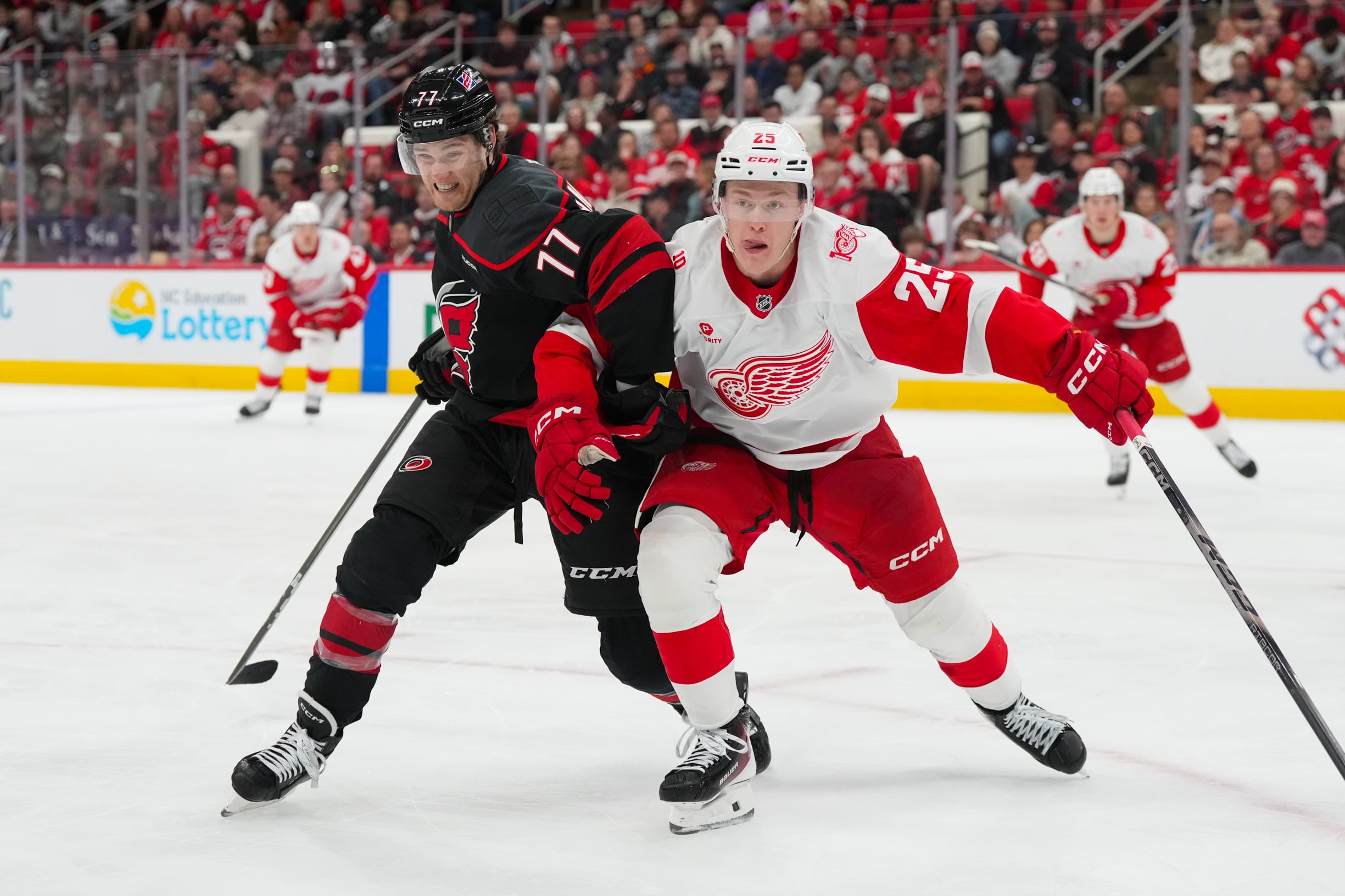 Dec 27, 2025; Raleigh, North Carolina, USA; Carolina Hurricanes center Jesperi Kotkaniemi (82) and Detroit Red Wings defenseman Jacob Bernard-Docker (25) battle for position during the third period at Lenovo Center. Mandatory Credit: James Guillory-Imagn Images