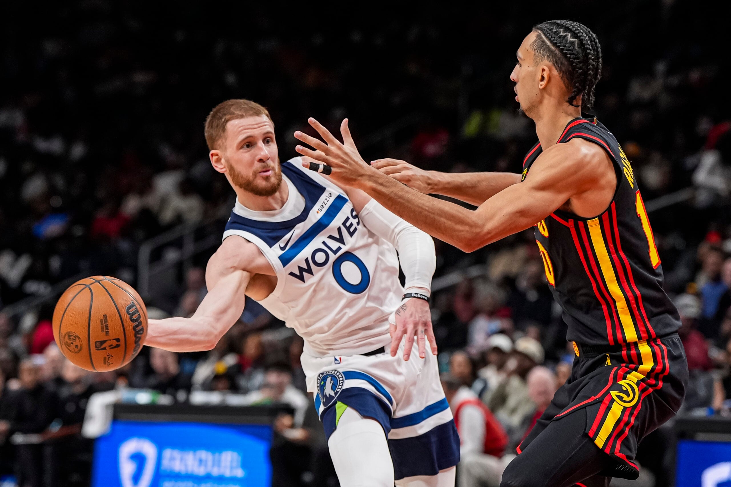 Dec 31, 2025; Atlanta, Georgia, USA; Minnesota Timberwolves guard Donte Divincenzo (0) passes the ball against Atlanta Hawks forward Zaccharie Risacher (10) during the second half at State Farm Arena. Mandatory Credit: Dale Zanine-Imagn Images