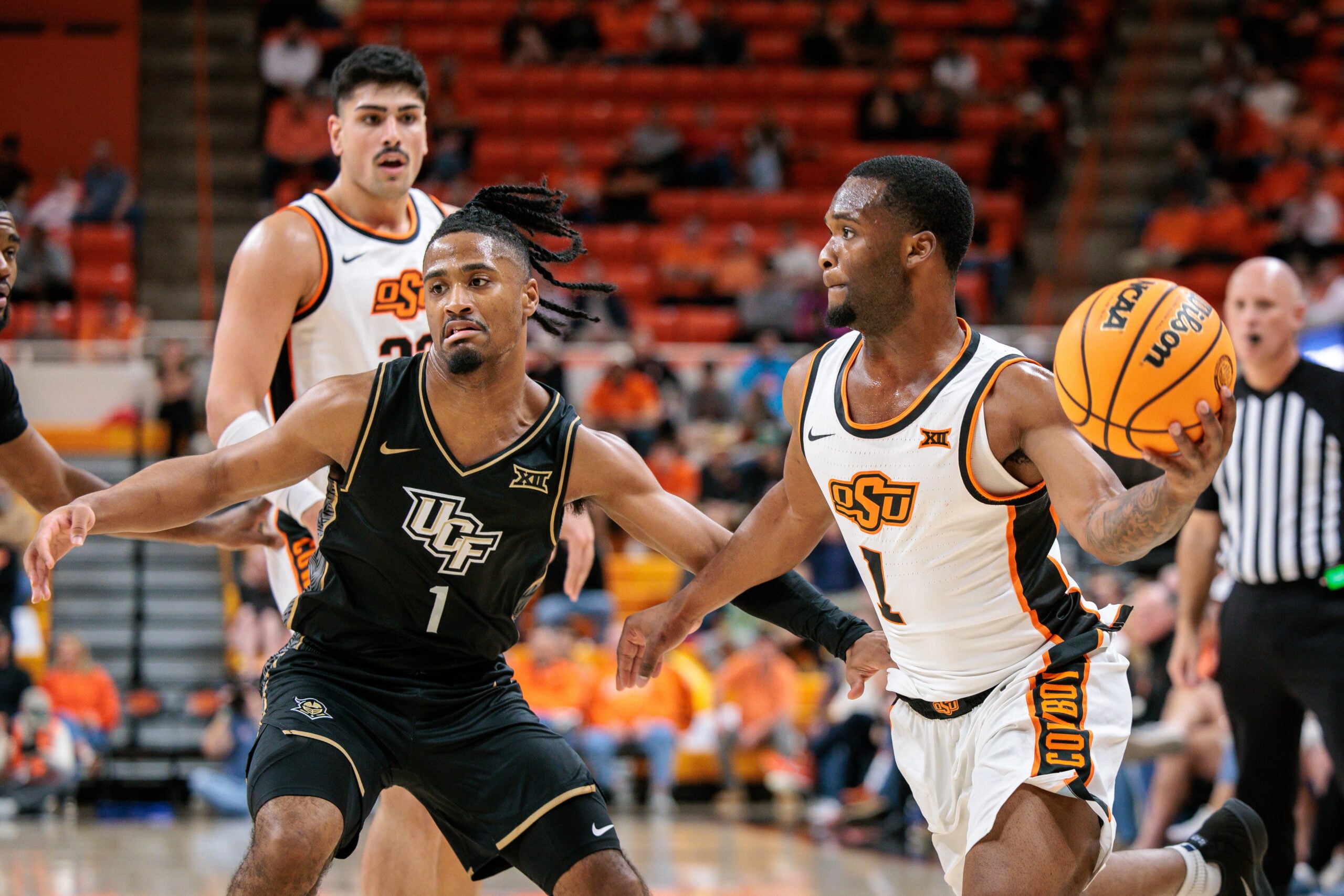Jan 6, 2026; Stillwater, Oklahoma, USA; Oklahoma State Cowboys guard Kanye Clary (1) passes the ball around UCF Knights guard Themus Fulks (1) during the first half at Gallagher-Iba Arena. Mandatory Credit: William Purnell-Imagn Images