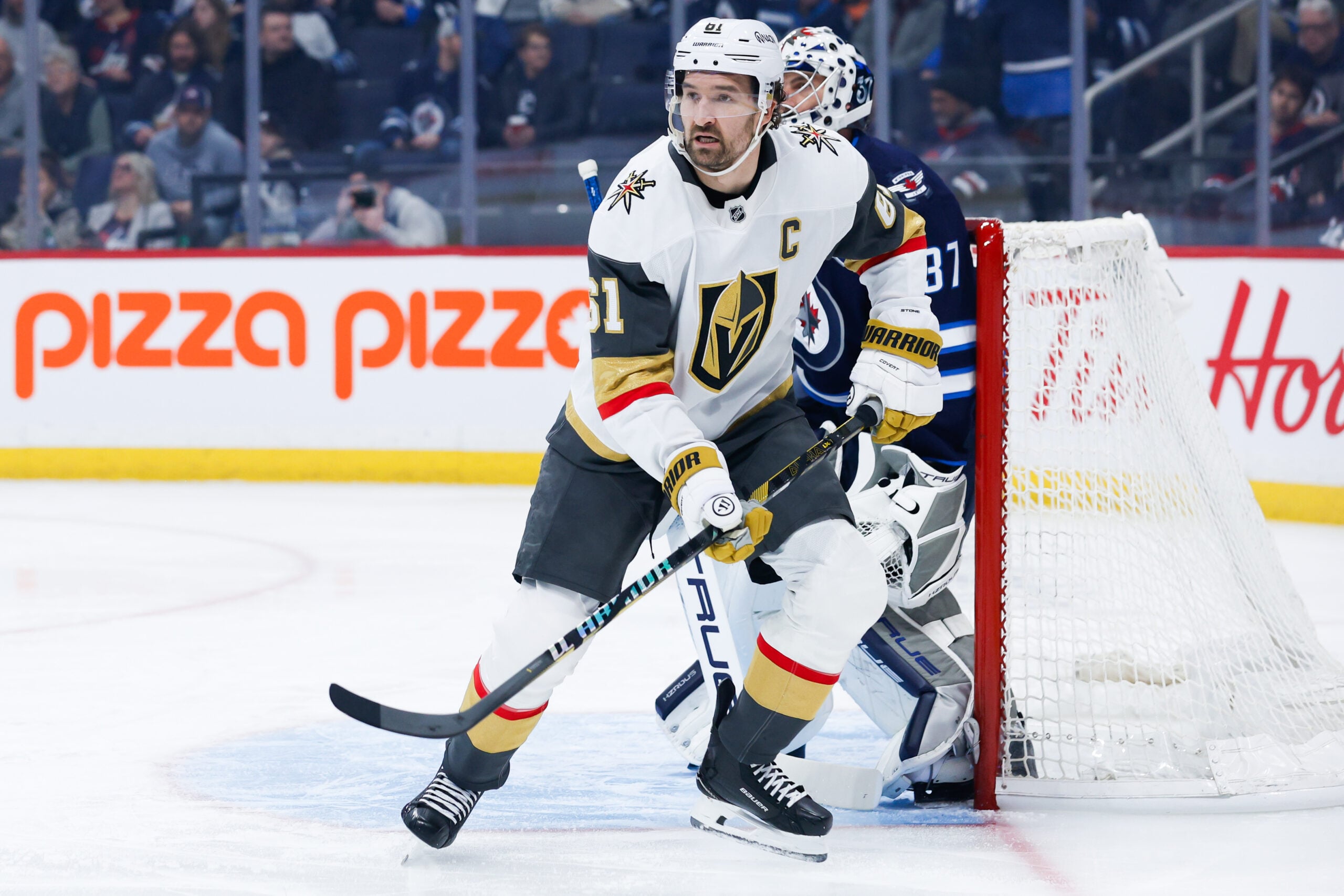 Jan 6, 2026; Winnipeg, Manitoba, CAN; Vegas Golden Knights forward Mark Stone (61) and Winnipeg Jets goalie Connor Hellebuyck (37) look for the puck during the first period at Canada Life Centre. Mandatory Credit: Terrence Lee-Imagn Images